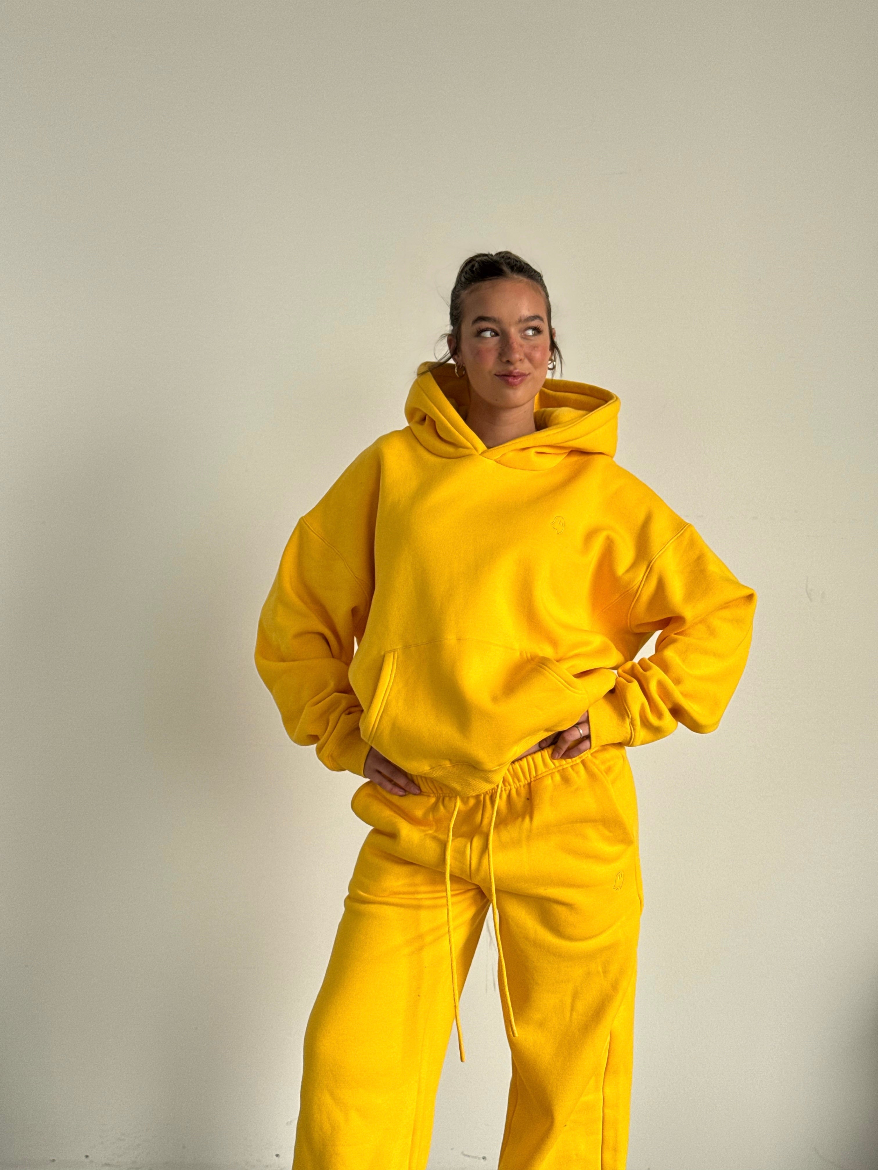 Person wearing a bright yellow hoodie and pants against a plain background