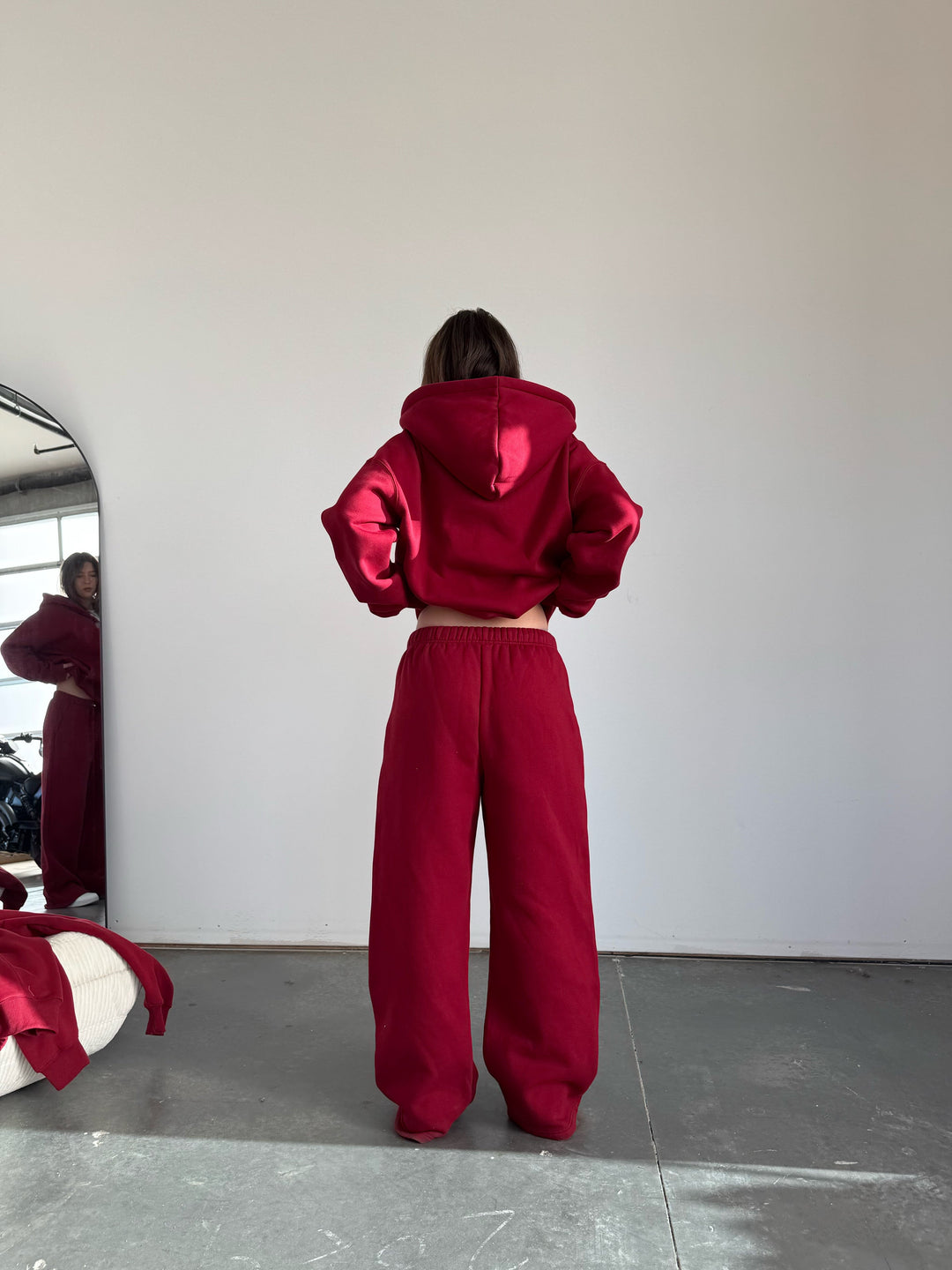 Person wearing a red tracksuit standing in front of a mirror.