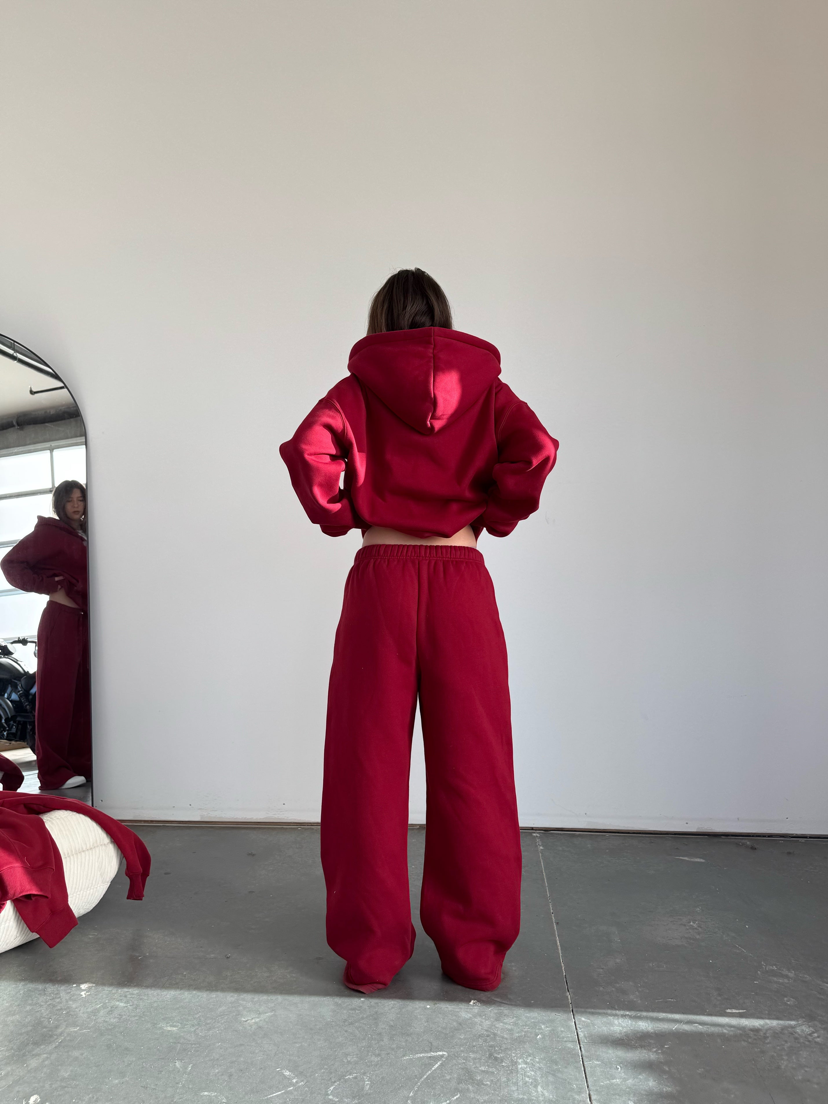 Person wearing a red tracksuit standing in front of a mirror.