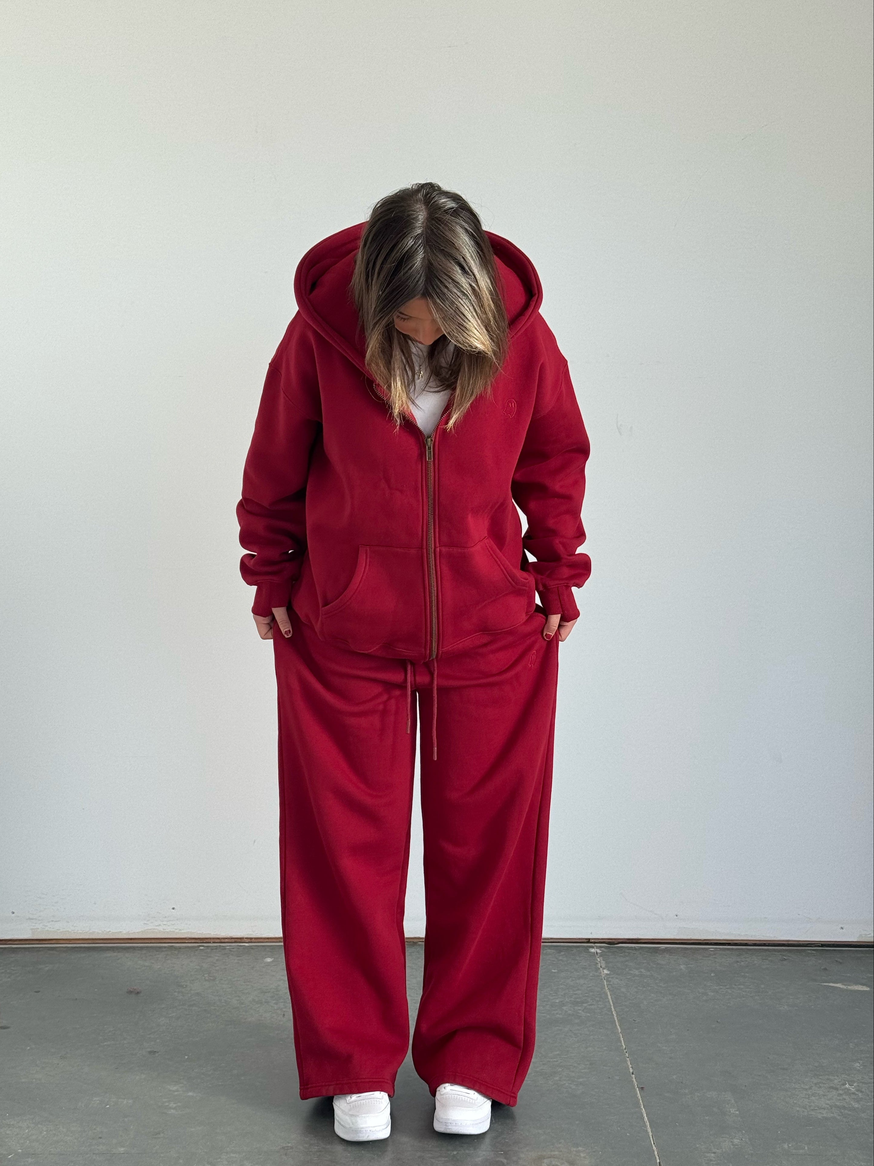 Person wearing a red tracksuit against a plain background
