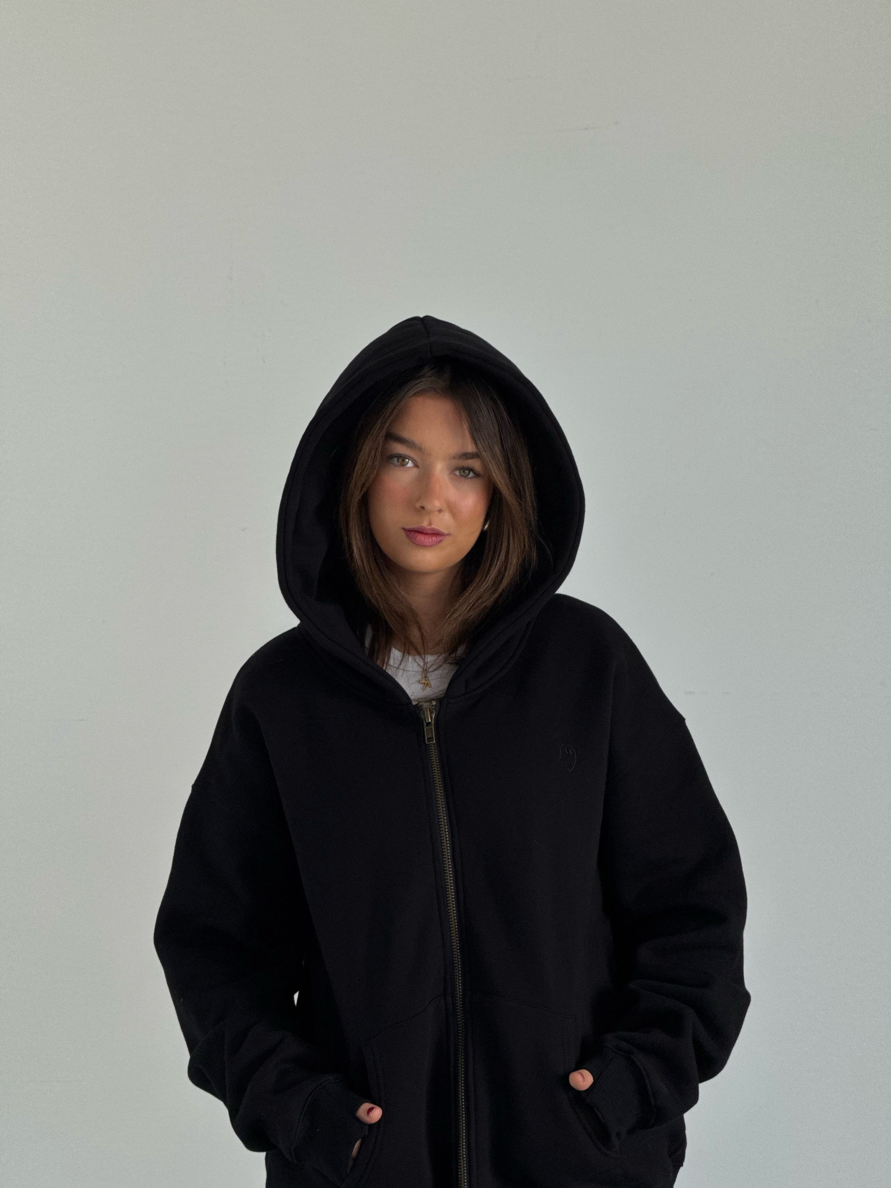 Person wearing a black hoodie against a plain background