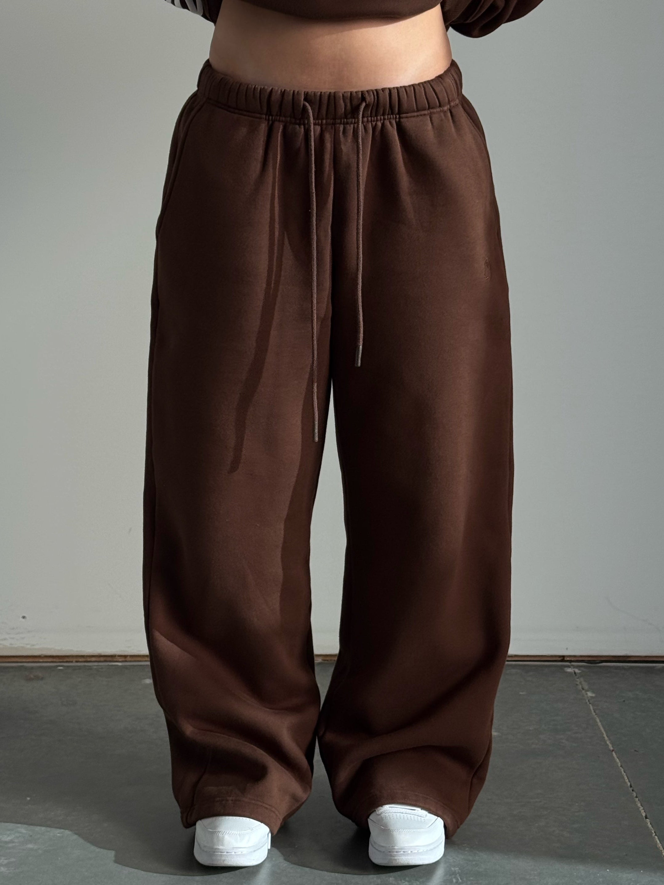 Brown sweatshirt and pants worn by a person on a gray floor with a neutral background