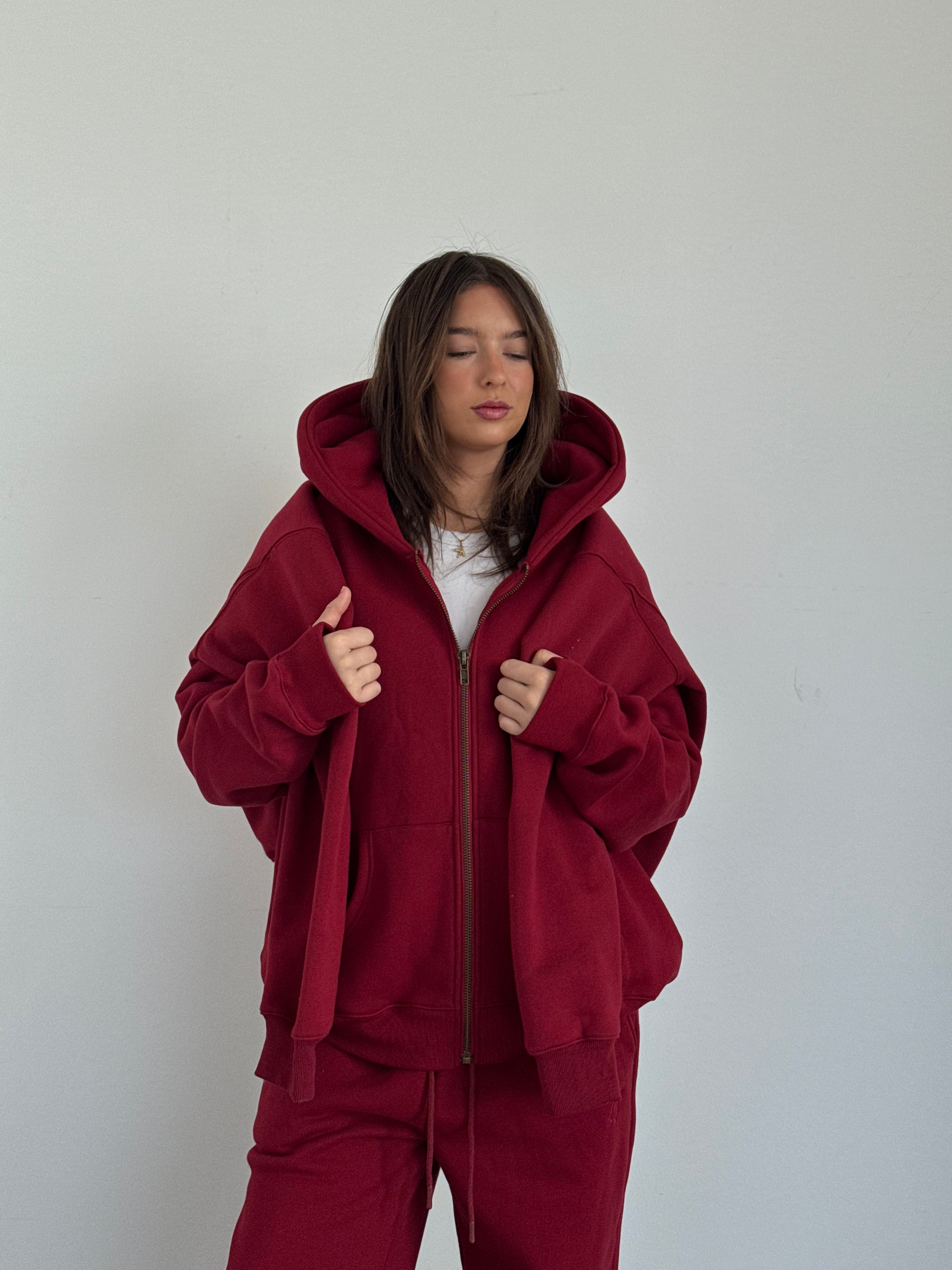 Person wearing a red hoodie and pants against a plain background