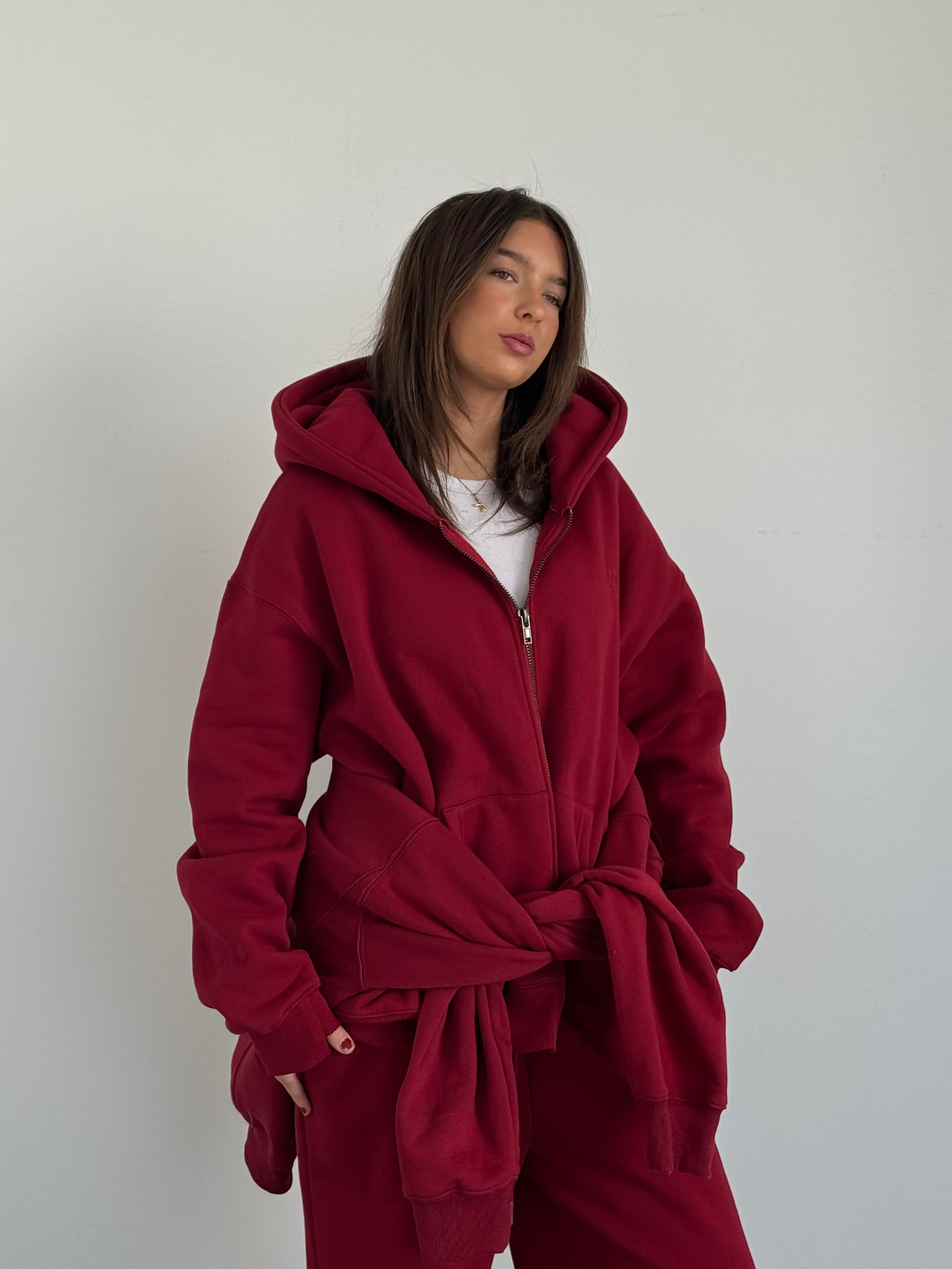 Person wearing a red hoodie and pants against a plain background