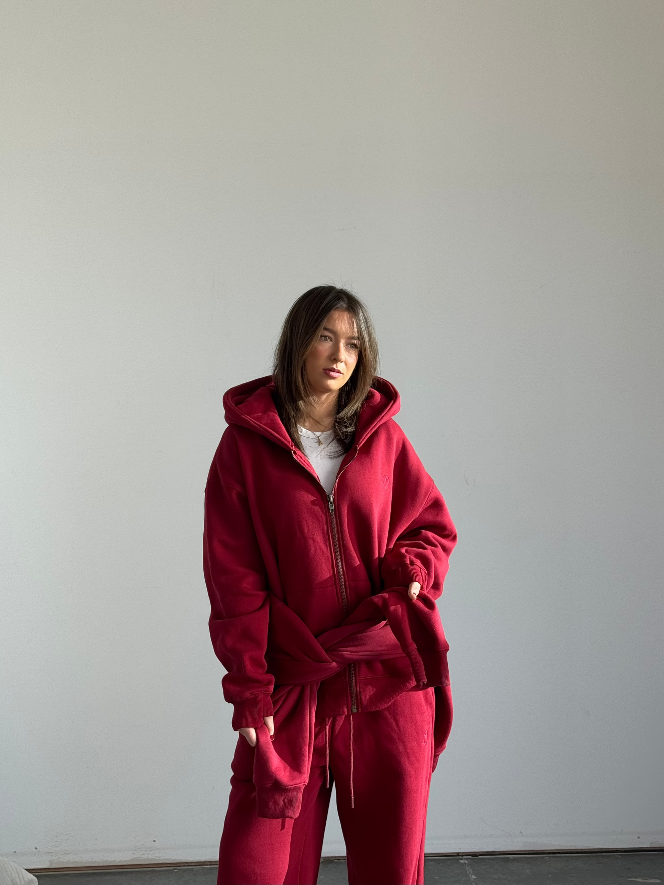 Person wearing a red tracksuit standing against a plain white wall.