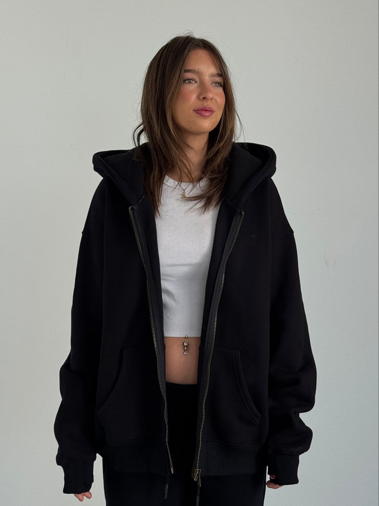 Person wearing a black hoodie and white shirt against a plain background
