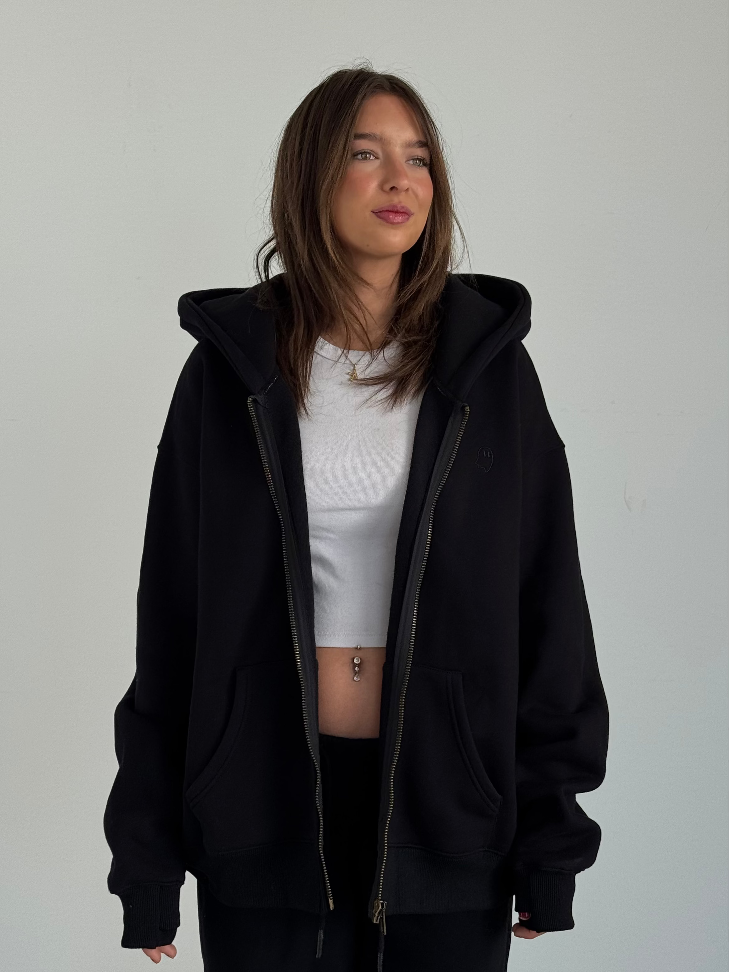 Person wearing a black hoodie and white shirt against a plain background
