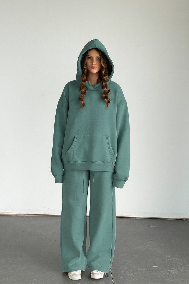 Person wearing a teal hoodie and pants set against a plain background