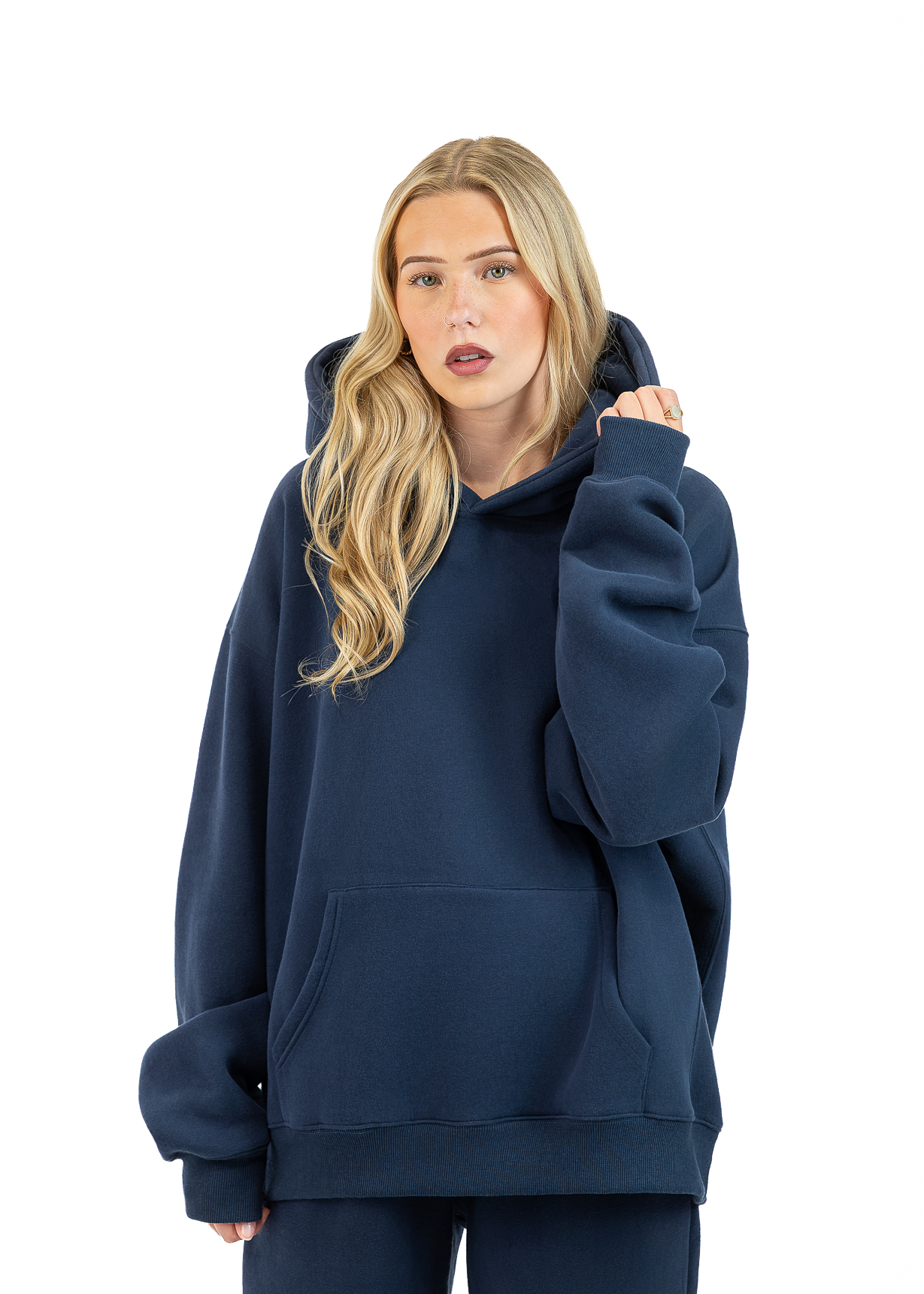 A blonde woman wearing an oversized navy blue pullover hoodie with a front kangaroo pocket, shown against a plain white background.