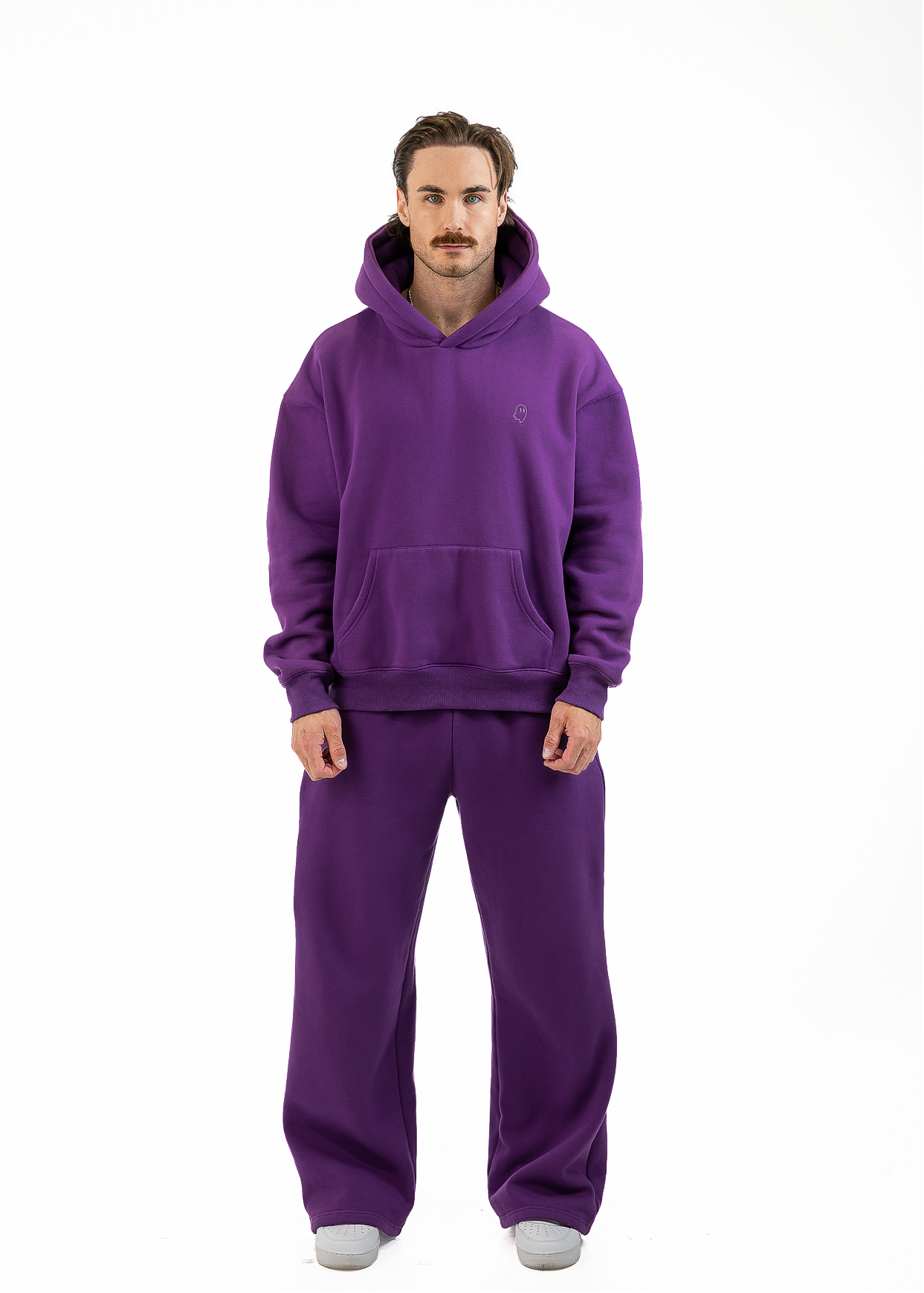 A man wearing a matching purple hoodie and sweatpants set, standing against a plain white background.