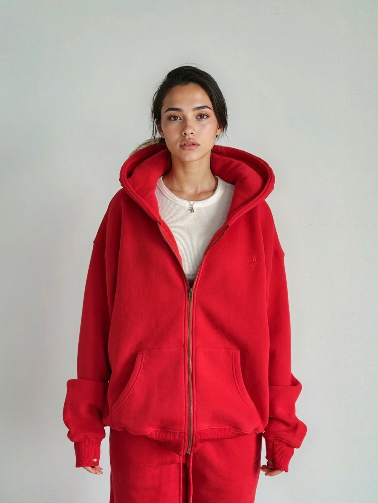 Person wearing a red hoodie and pants on a plain background