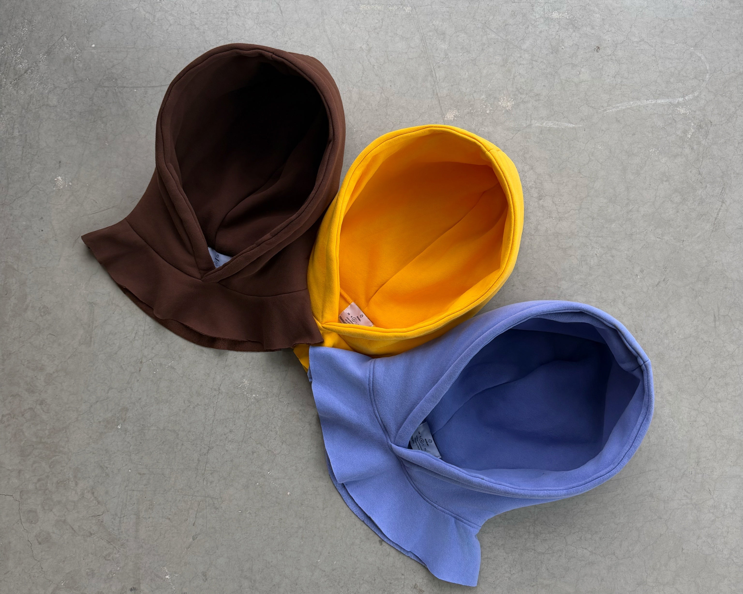 Three colorful hats (brown, yellow, blue) on a gray surface