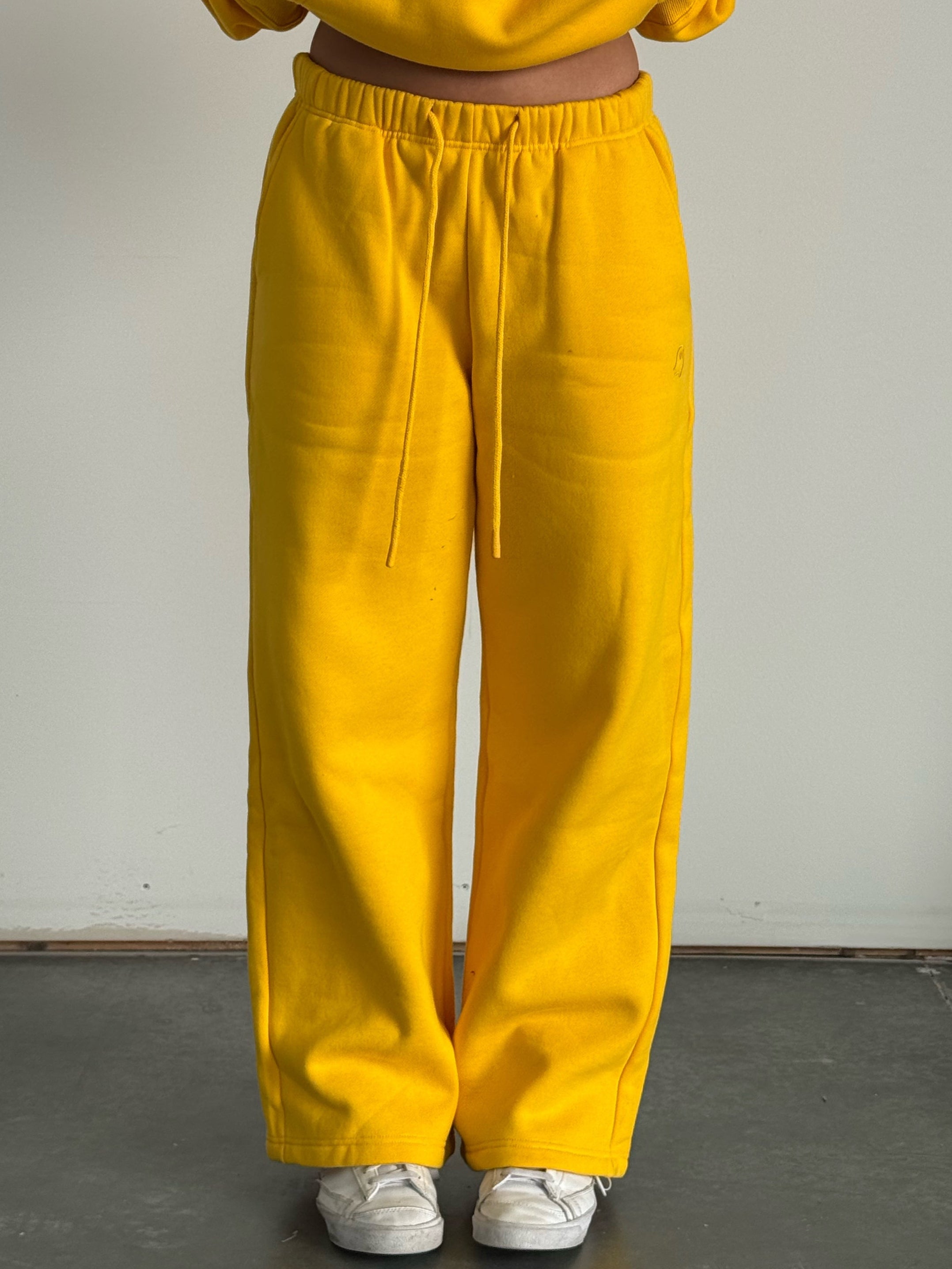Person wearing a yellow hoodie and matching pants against a plain background