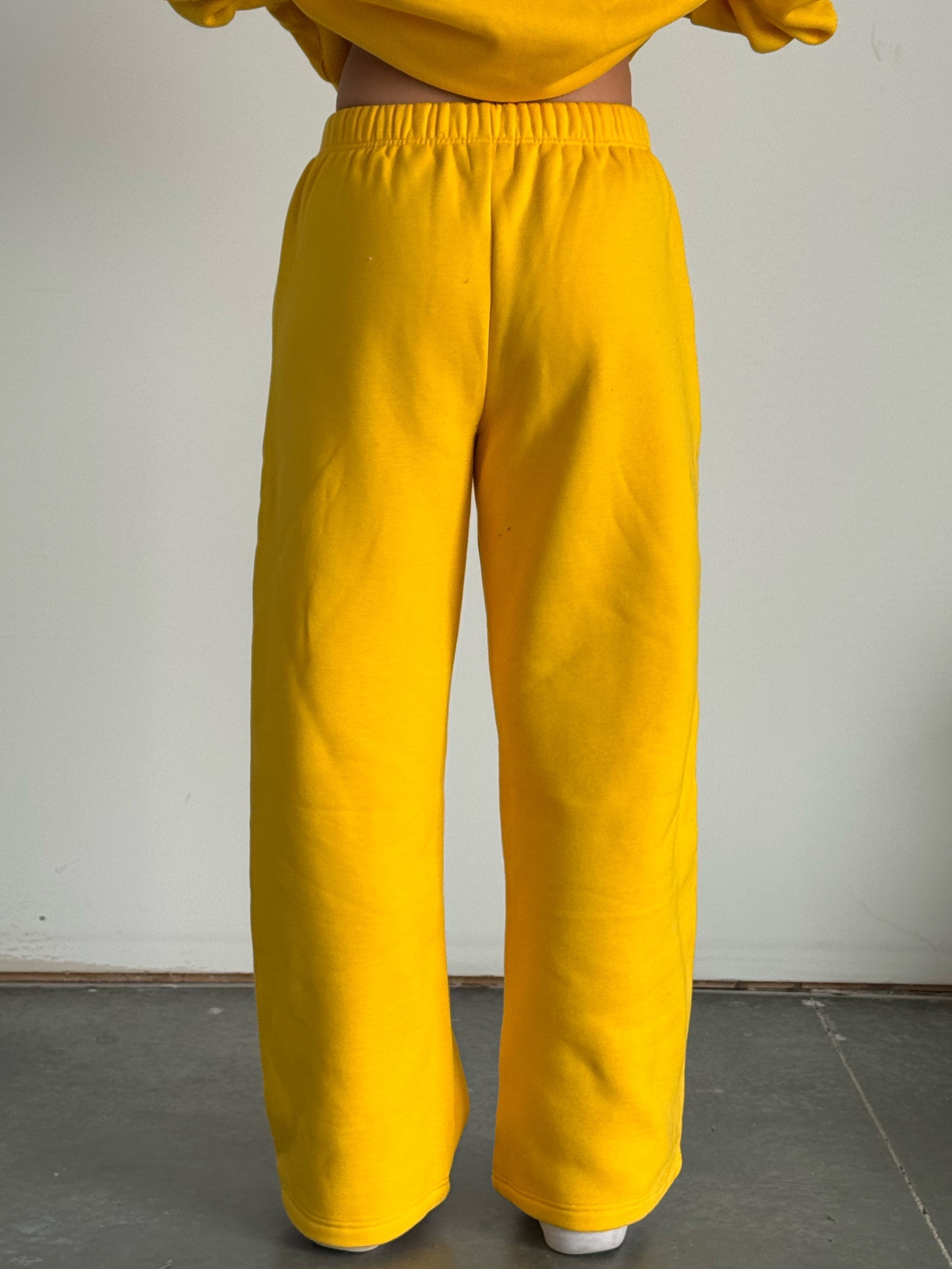 Person wearing a yellow tracksuit against a plain background