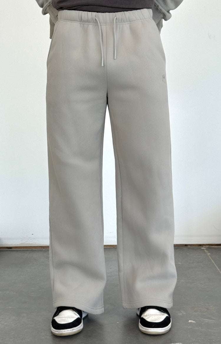 Person wearing light gray pants and a dark shirt against a white wall.