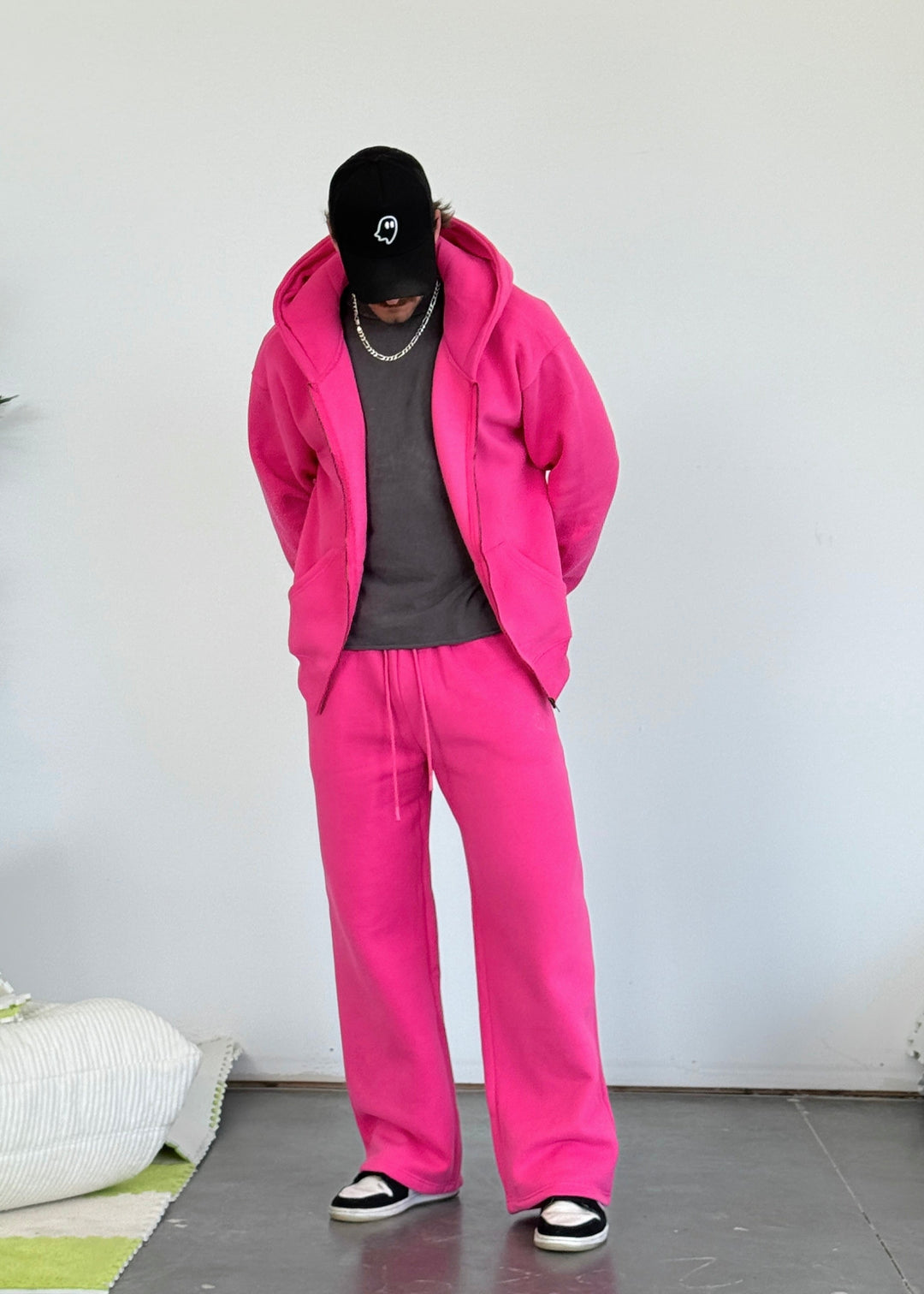 Person wearing a bright pink tracksuit with a plain white background