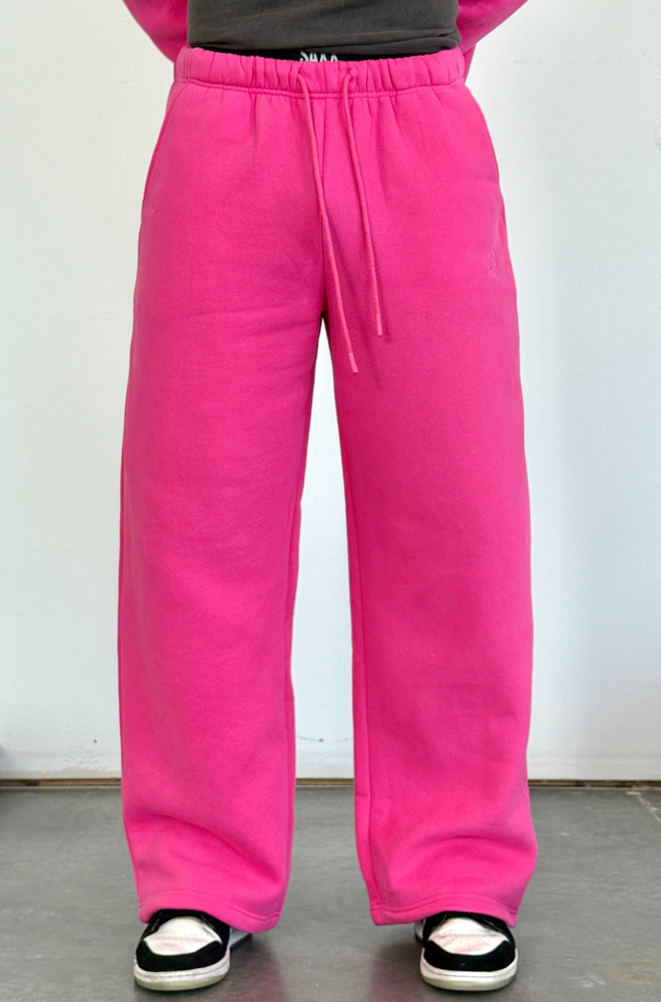 Person wearing bright pink sweatpants with a plain background
