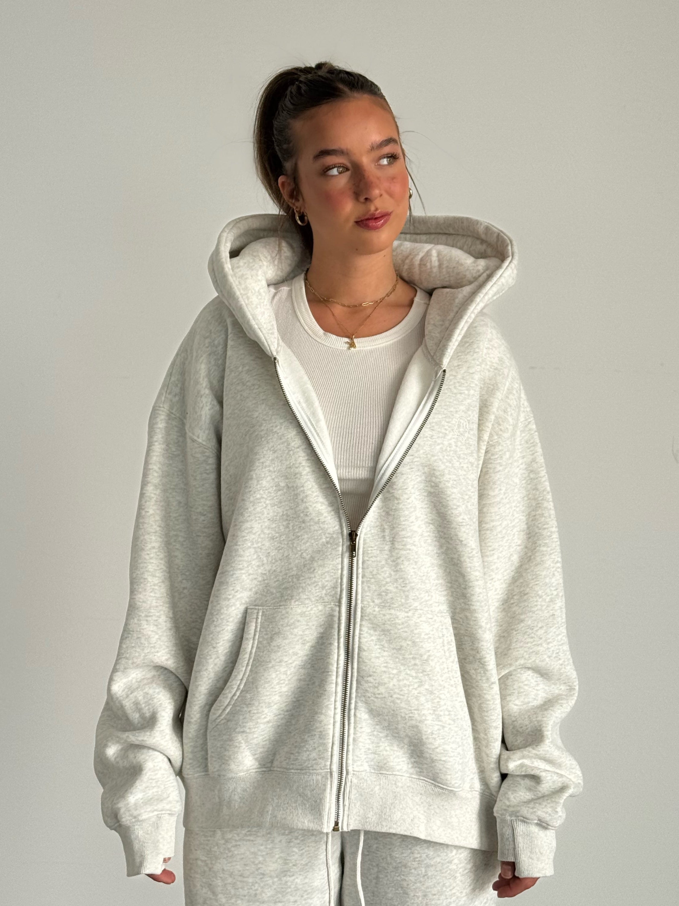 Person wearing a gray hoodie and pants on a plain background