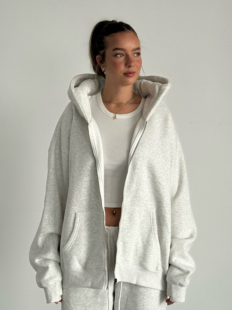Person wearing a gray hoodie and pants on a plain background