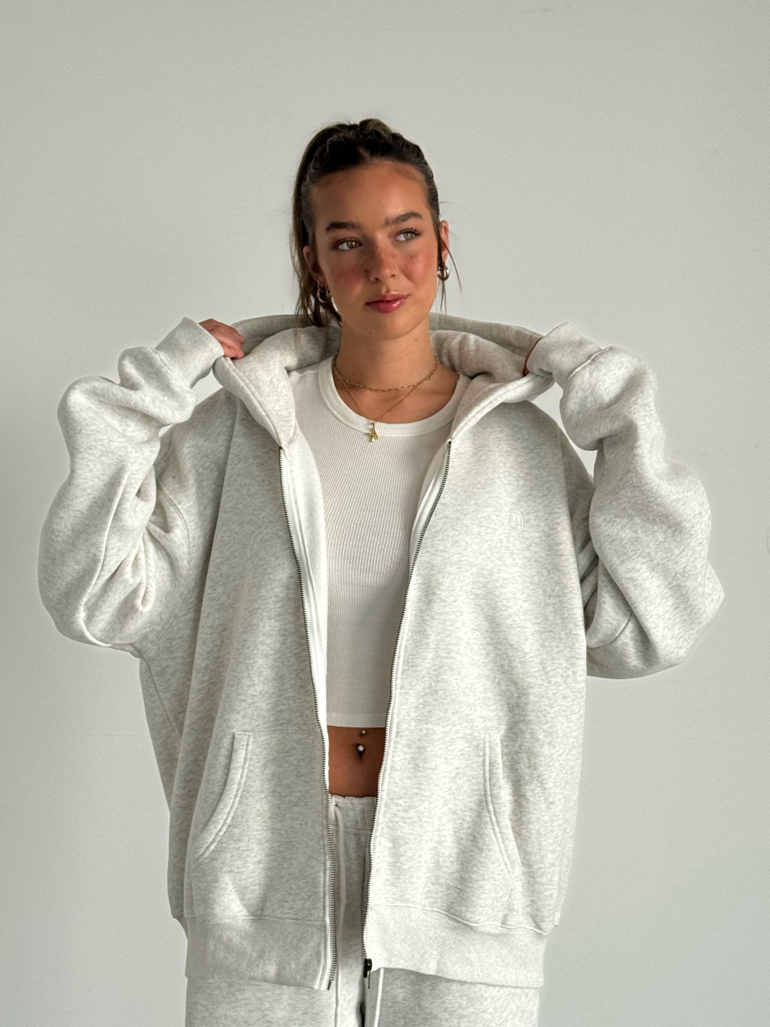 Person wearing a gray tracksuit against a plain background