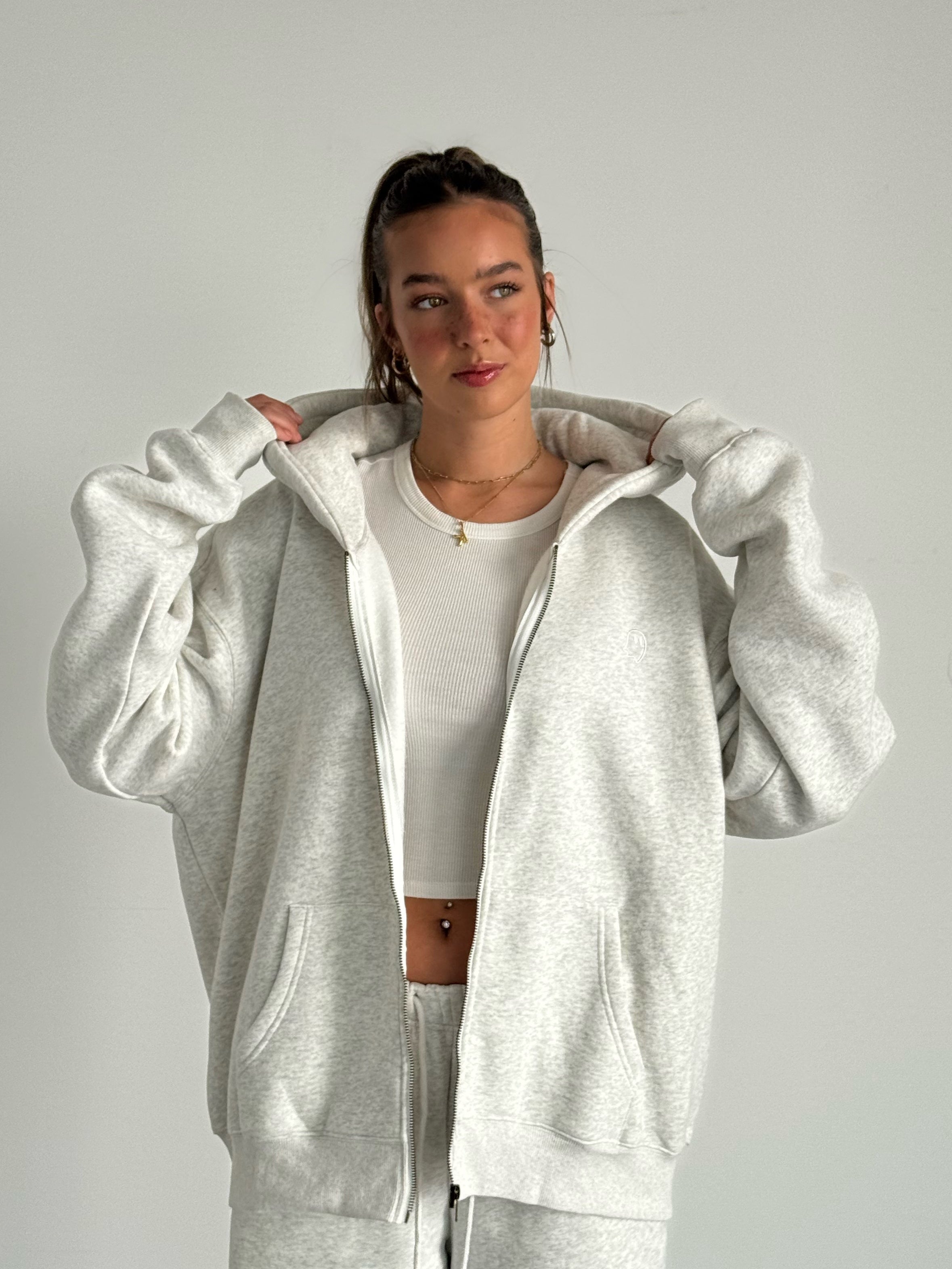 Person wearing a gray tracksuit against a plain background