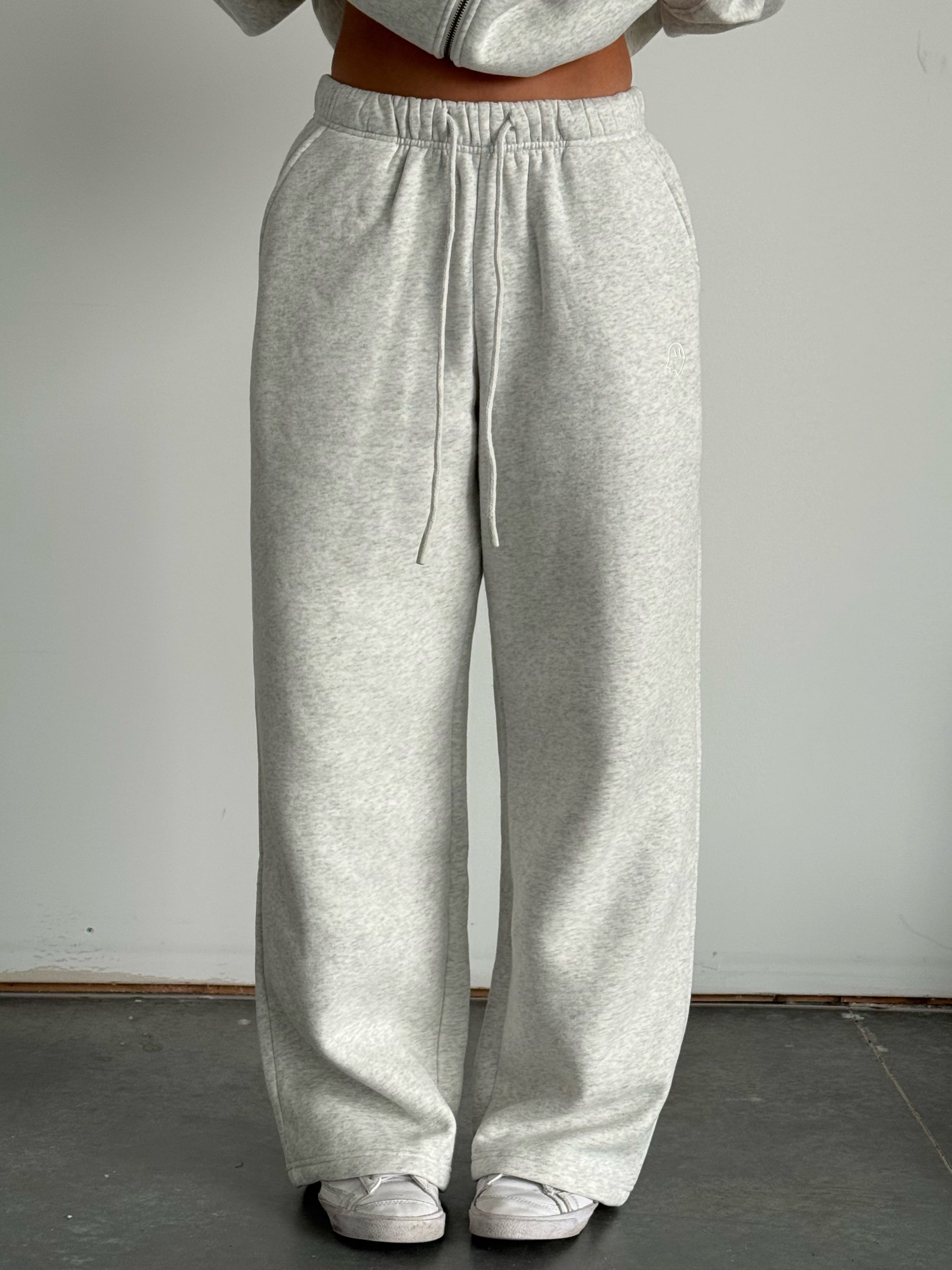 Person wearing gray sweatpants and a matching hoodie against a plain background
