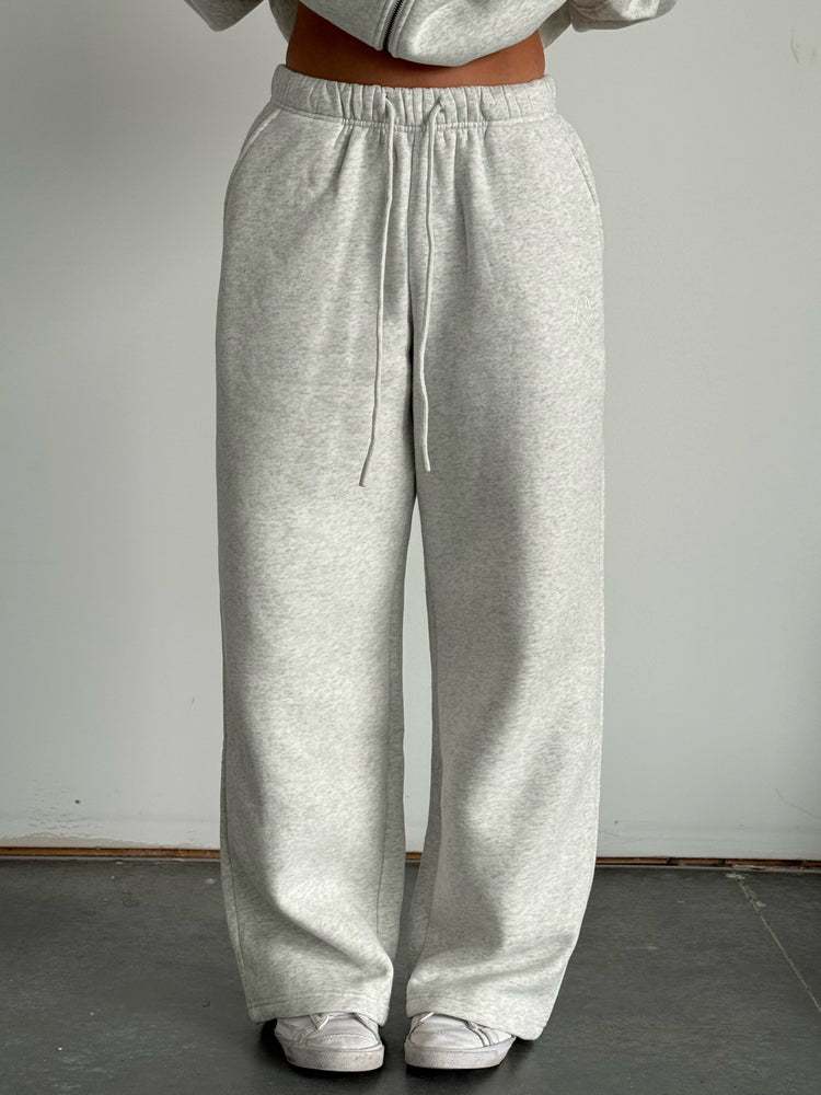 Person wearing gray sweatpants and a matching hoodie against a plain background