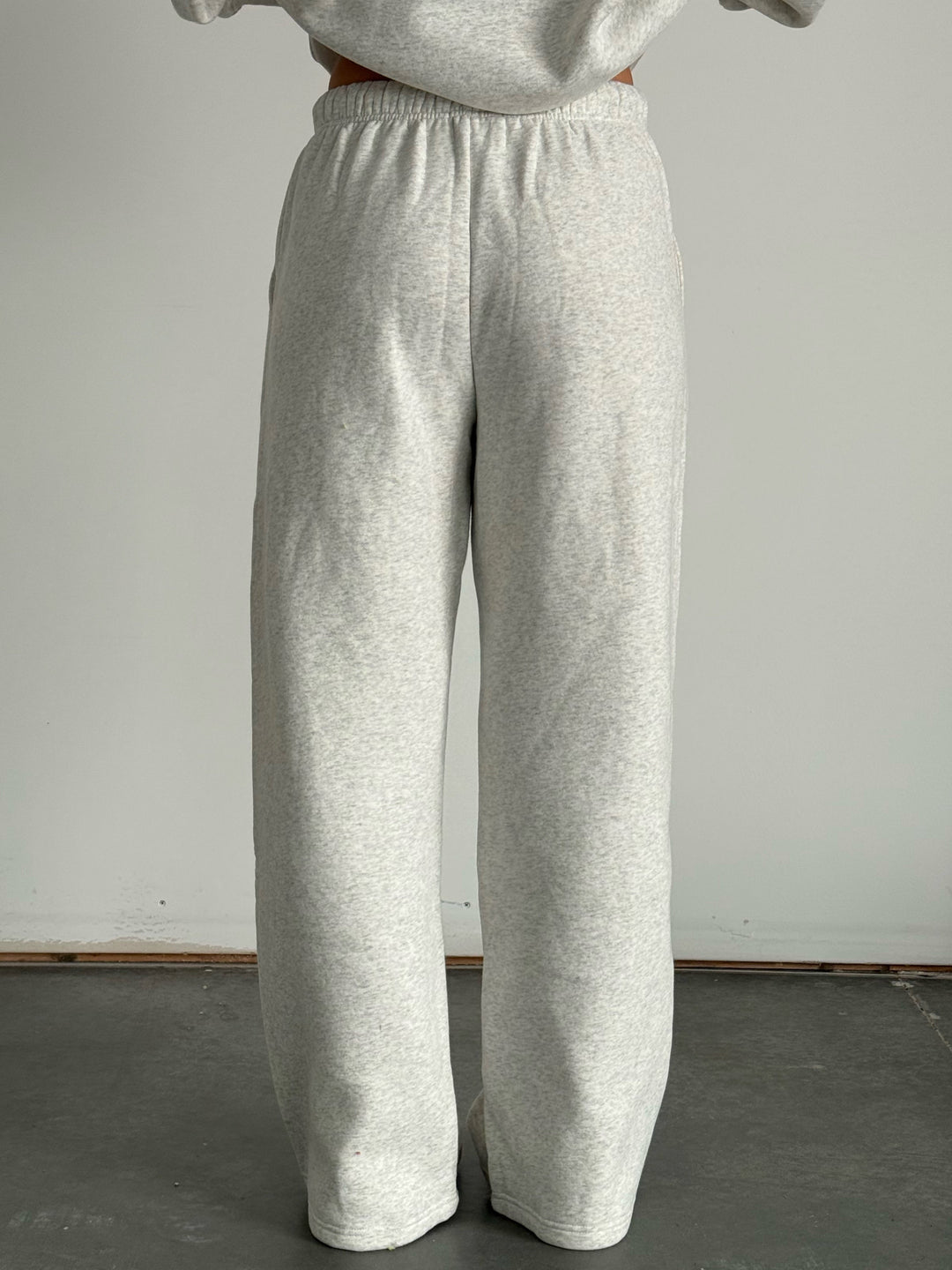 Person wearing gray sweatpants and a matching sweatshirt against a plain background