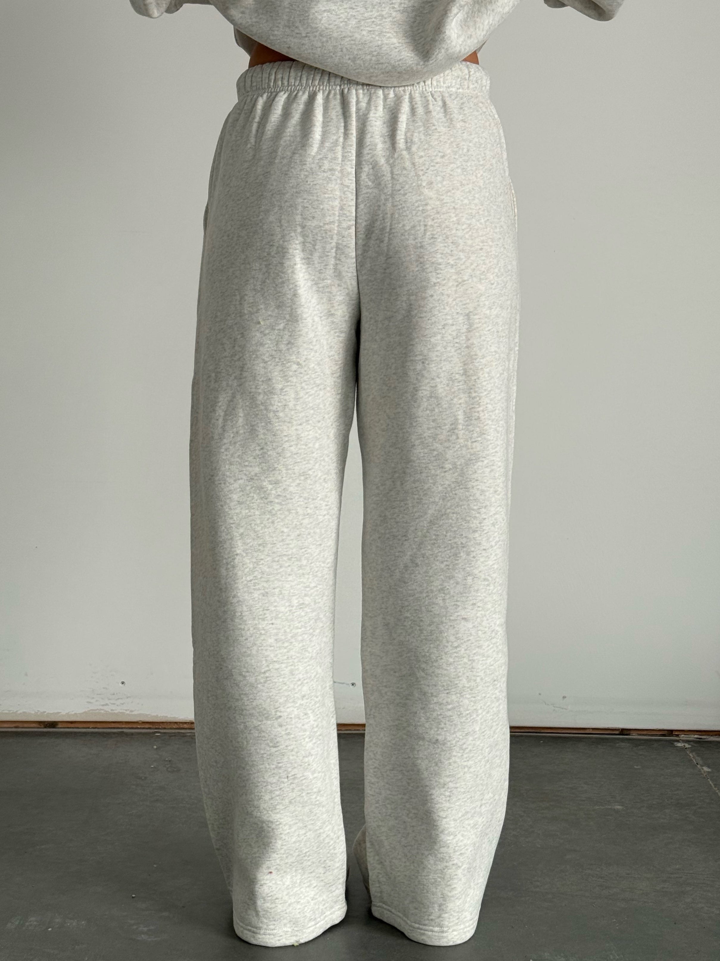 Person wearing gray sweatpants and a matching sweatshirt against a plain background
