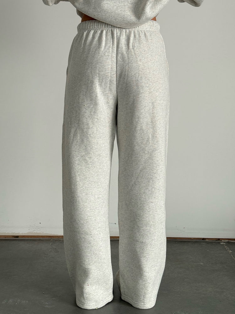 Person wearing gray sweatpants and a matching sweatshirt against a plain background