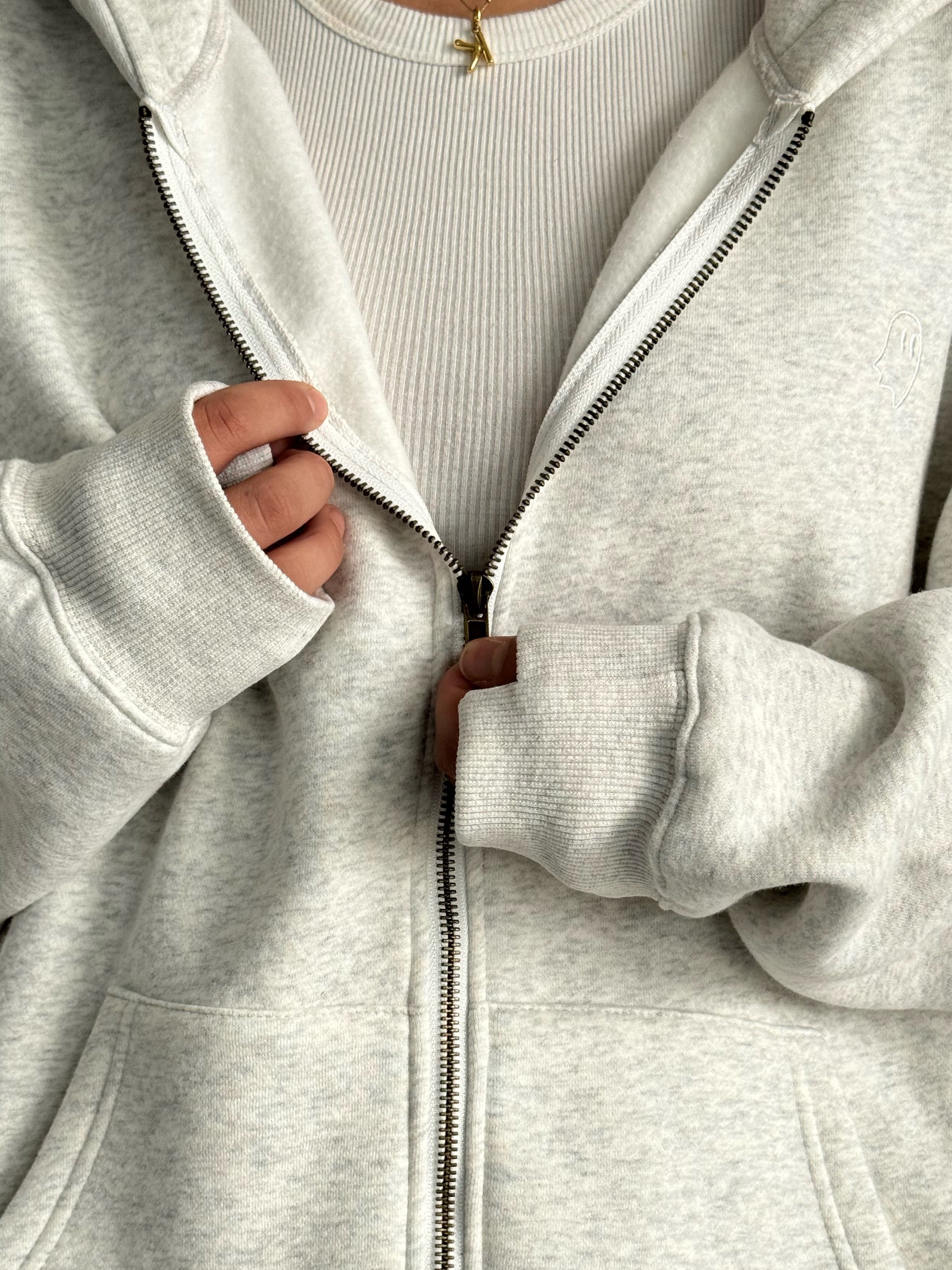 Close-up of a gray zip-up hoodie being unzipped