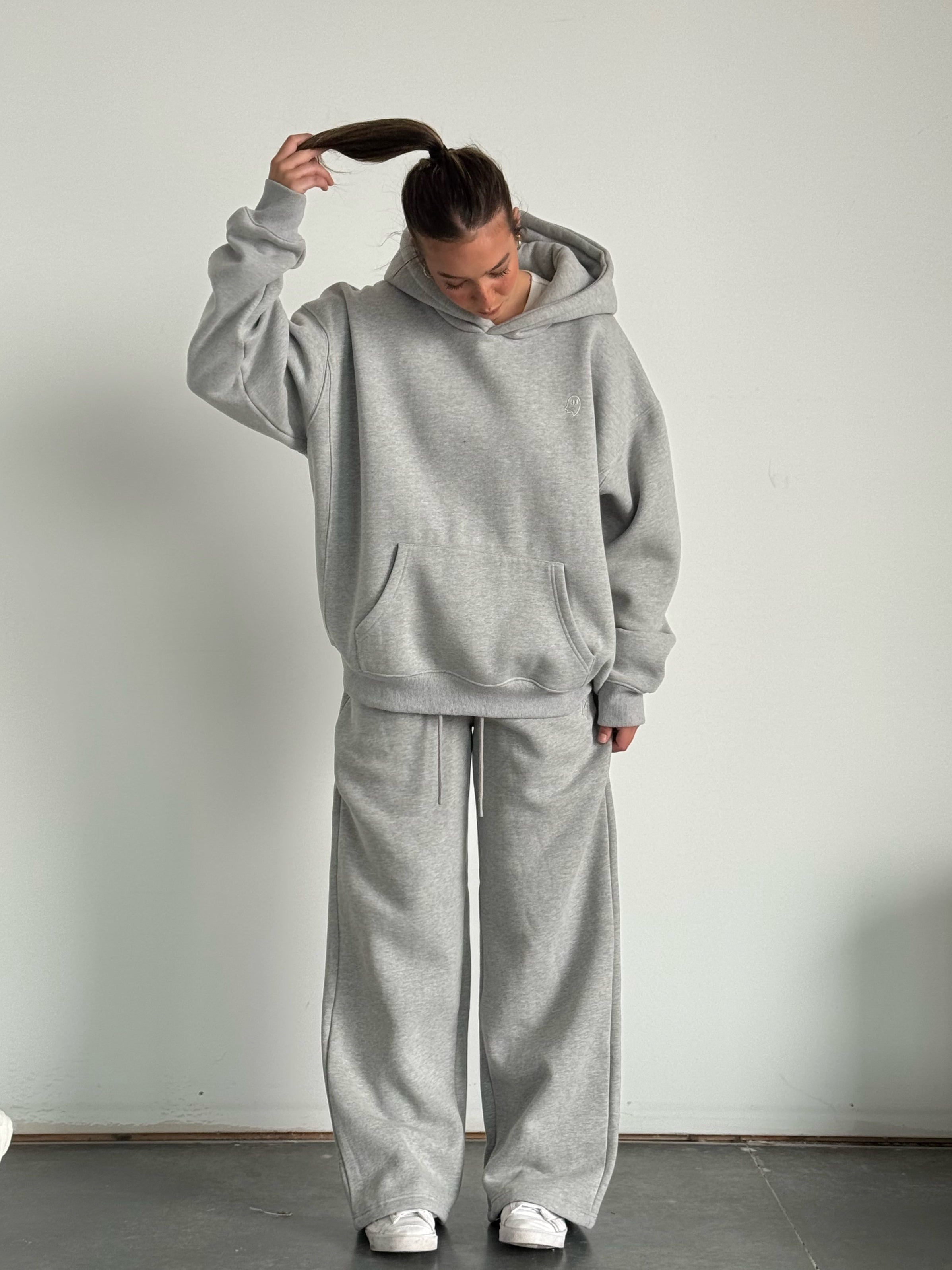 Person wearing a gray tracksuit against a plain background