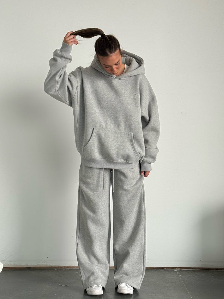 Person wearing a gray tracksuit against a plain background