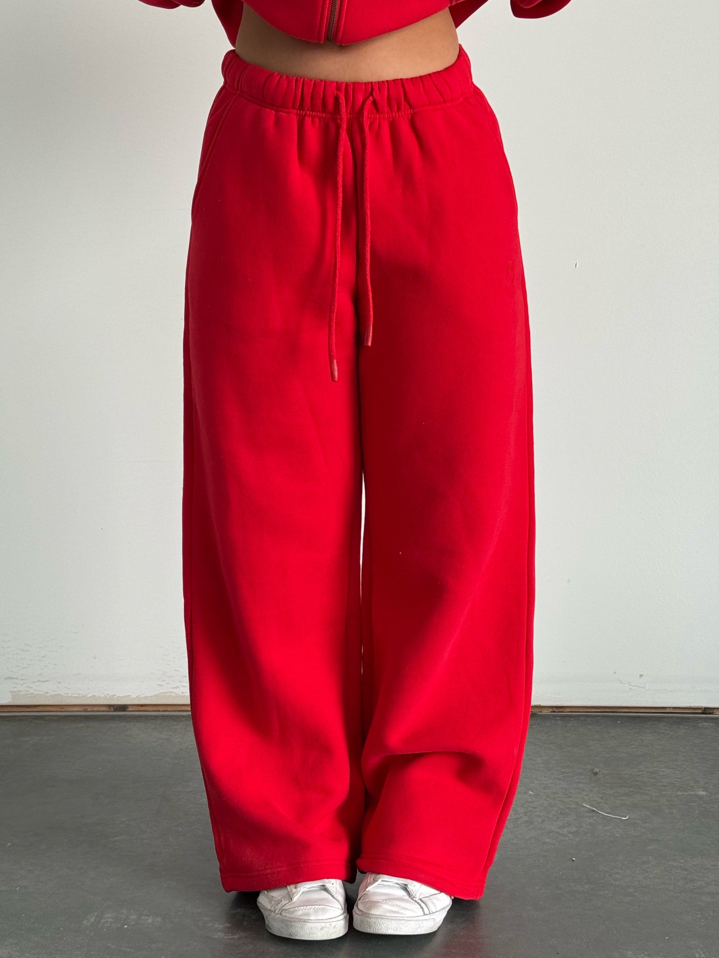 Red tracksuit worn by a person on a plain background