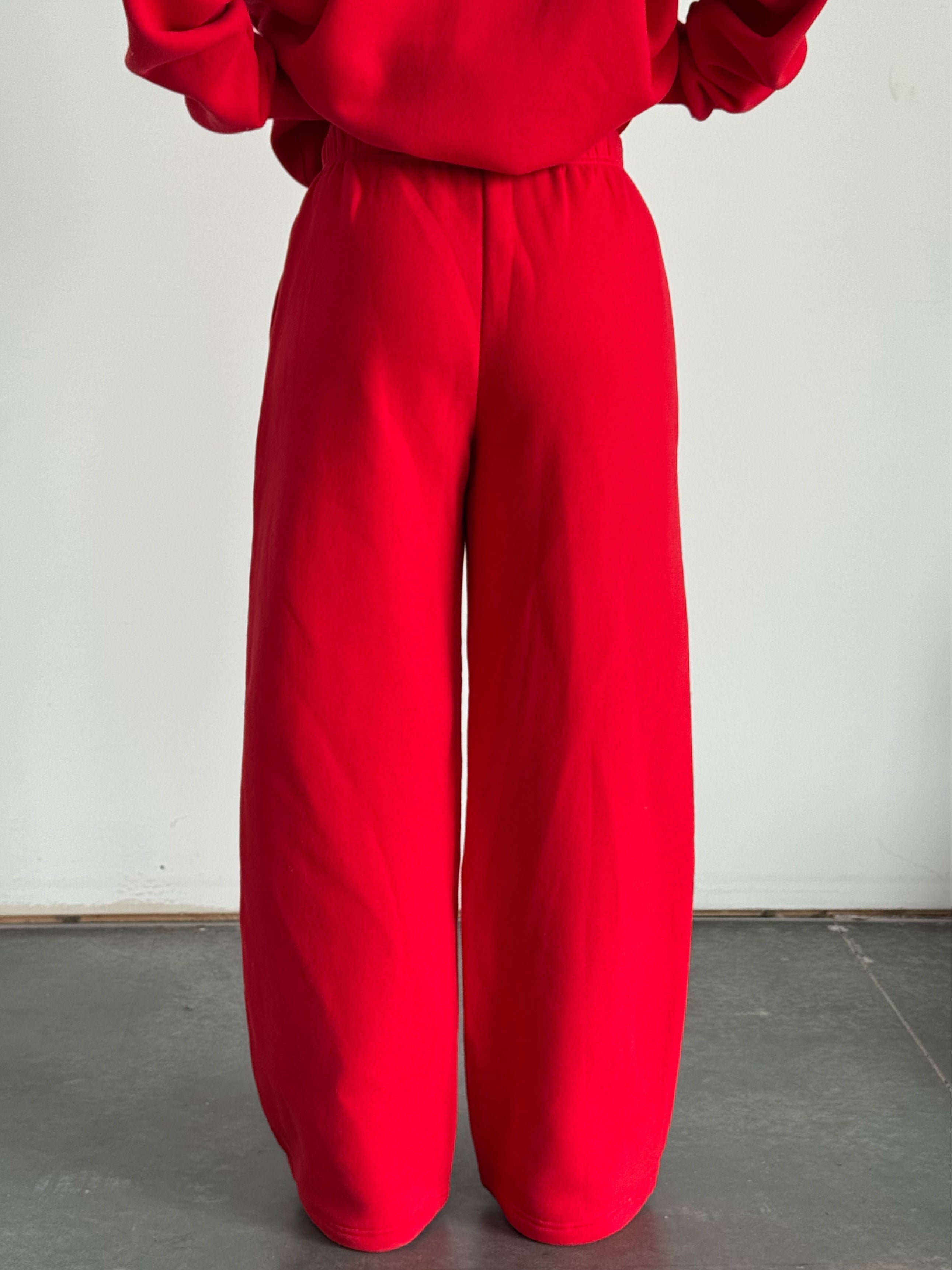 Person wearing a red outfit with wide-legged pants on a plain background