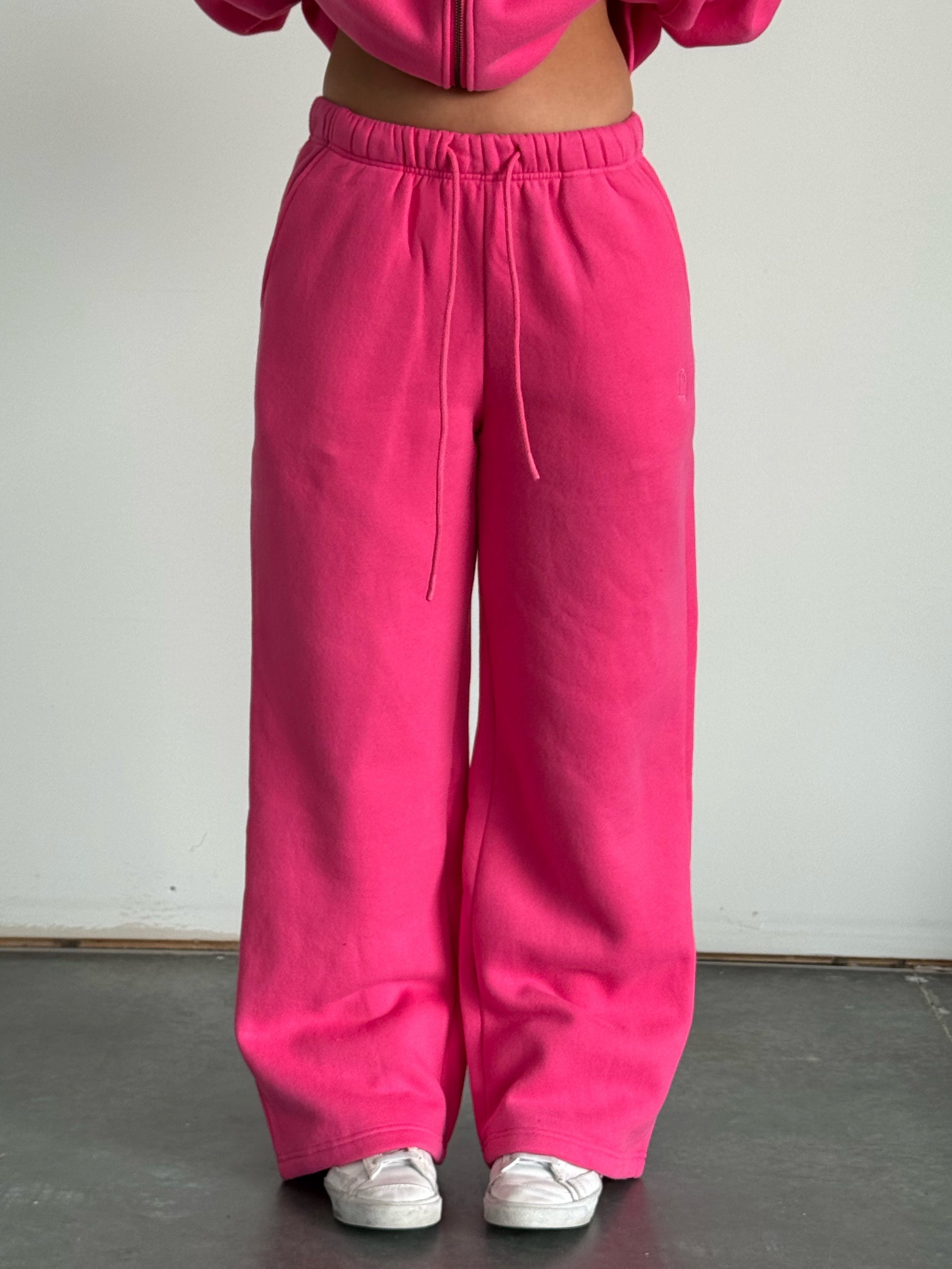 Person wearing a bright pink tracksuit against a plain background