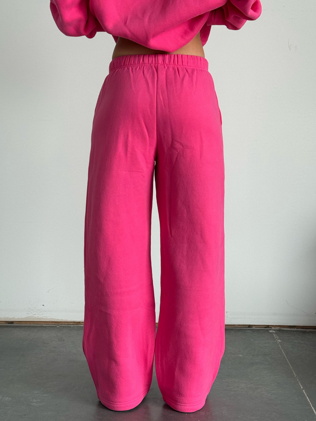 Person wearing a bright pink outfit with a matching top and pants against a plain background