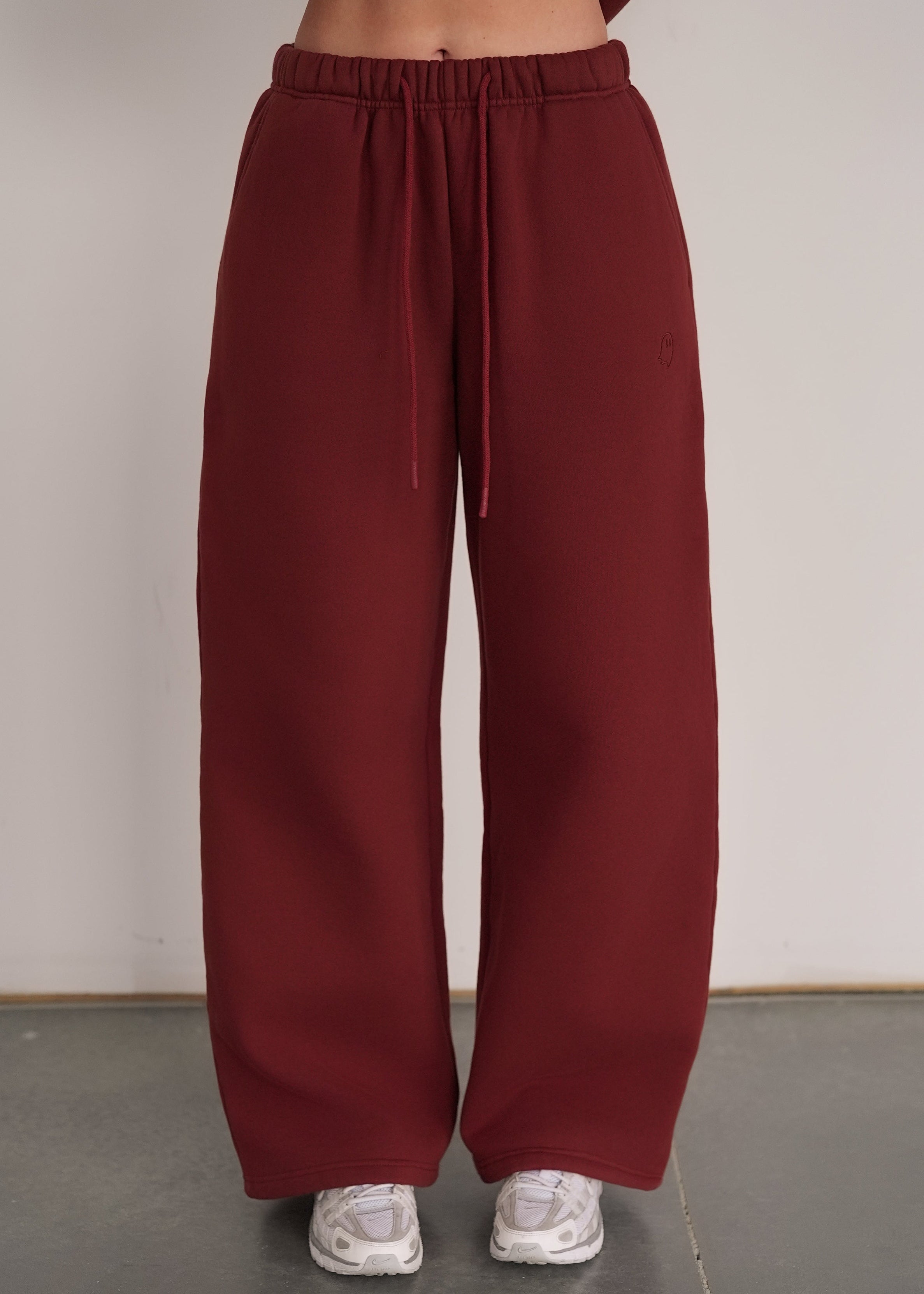 Maroon sweatpants worn by a person on a plain background