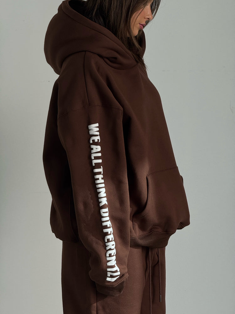 Brown hoodie with text on sleeve against a plain background