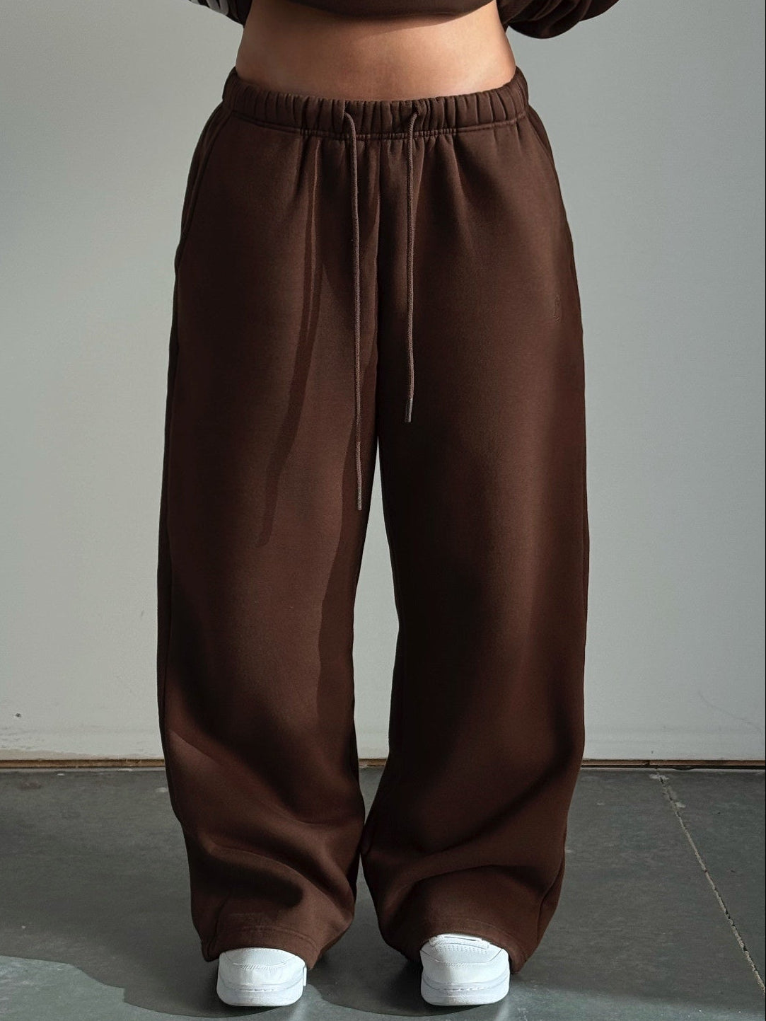 Brown sweatshirt and pants worn by a person against a plain background