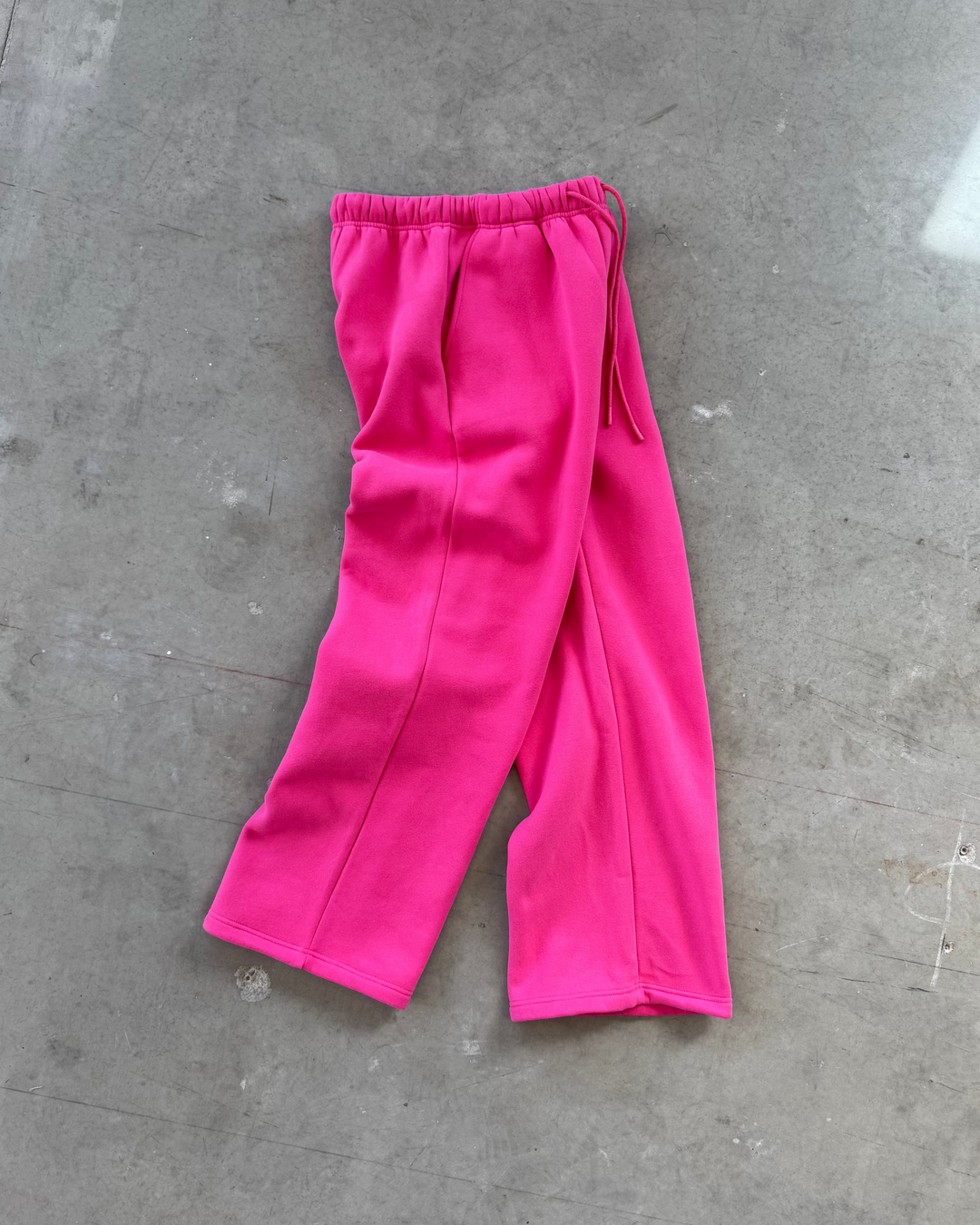 Bright pink pants on a gray concrete floor