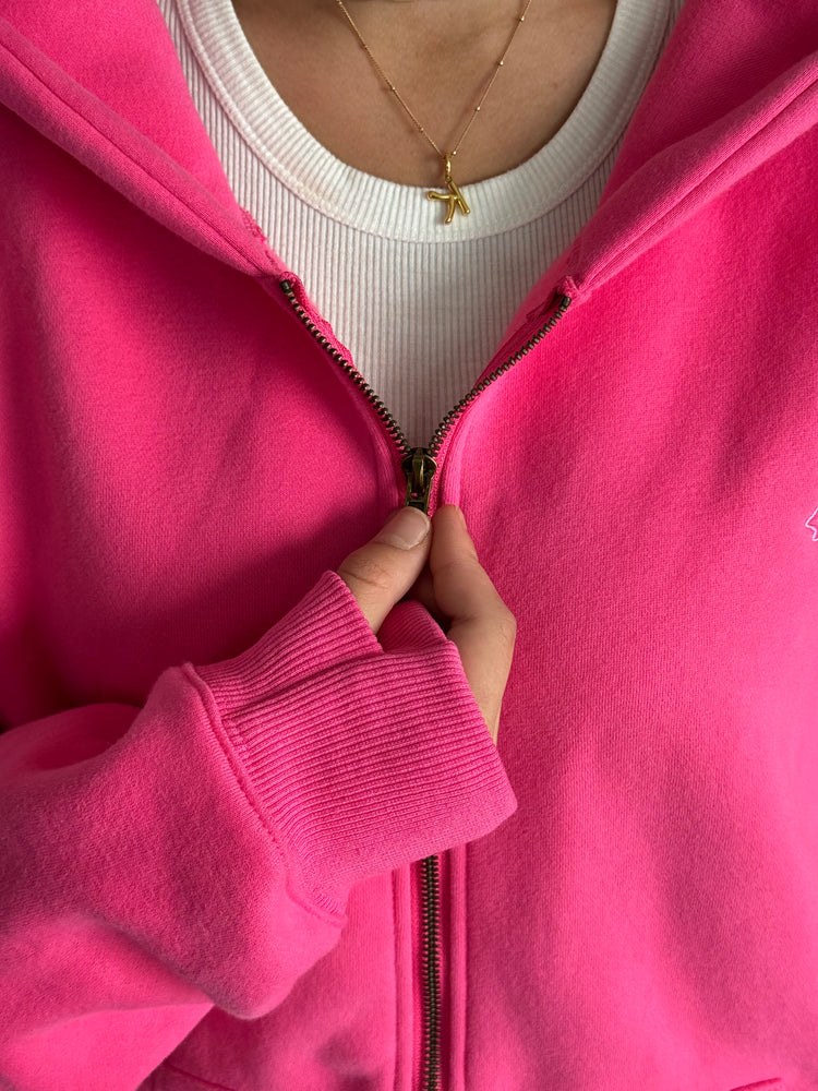 Person wearing a bright pink zip-up hoodie over a white shirt.