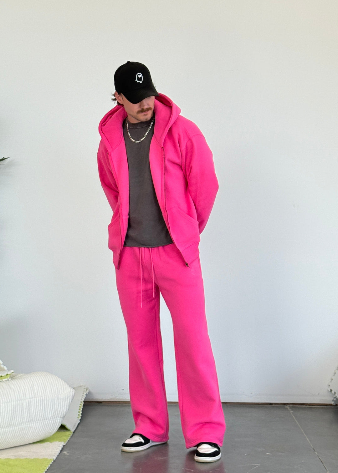 Person wearing a bright pink tracksuit with a plain white background