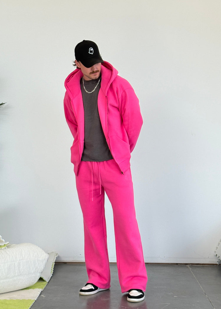 Person wearing a bright pink tracksuit with a plain white background
