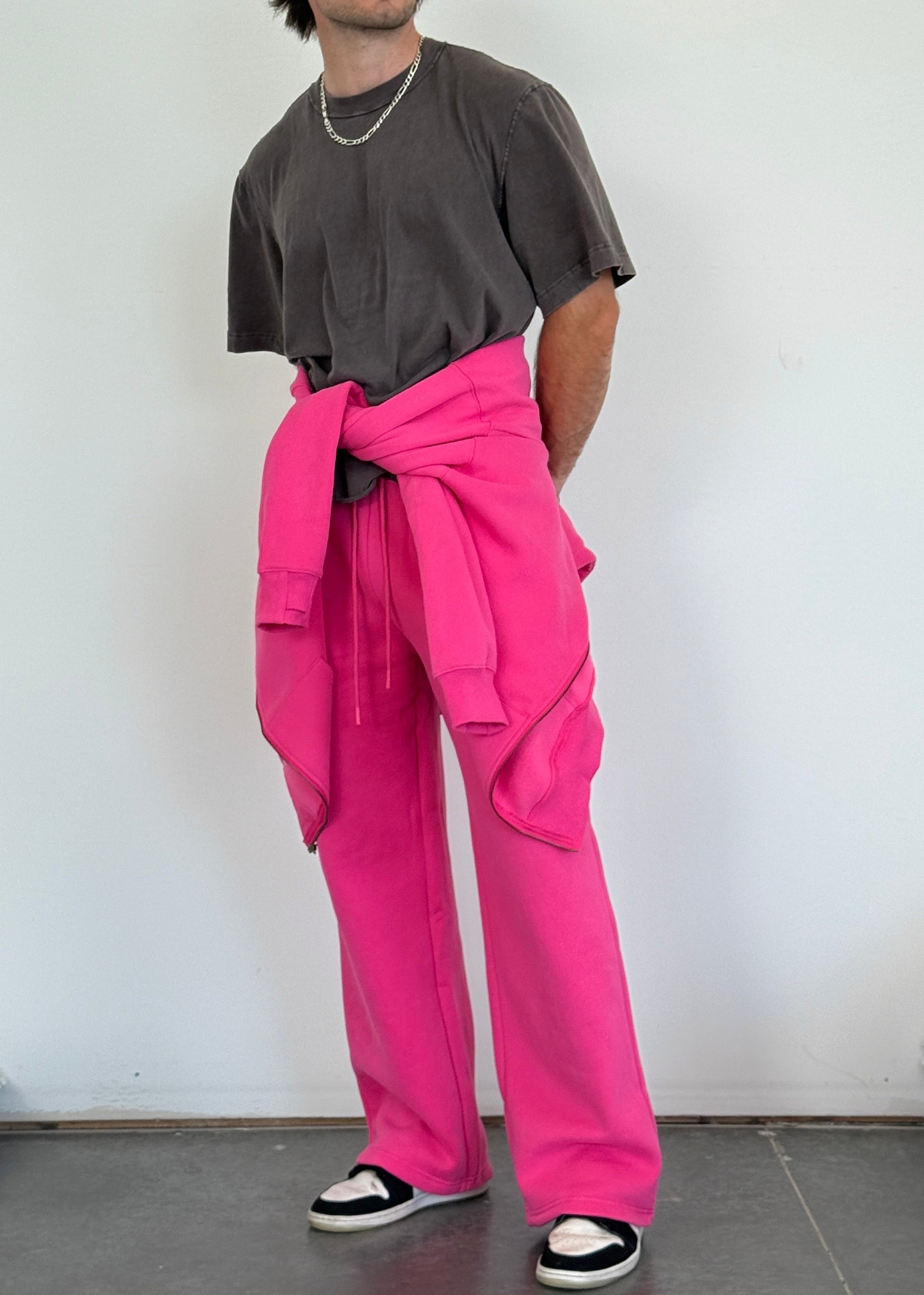 Person wearing a dark shirt, pink pants, and a black cap against a white background