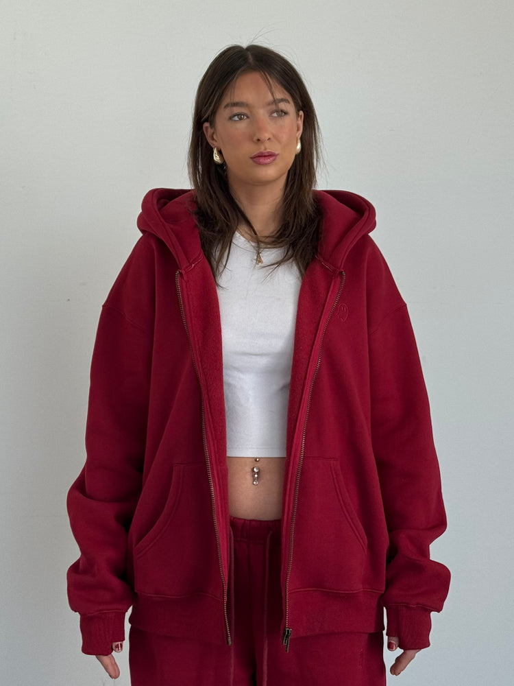 Person wearing a red hoodie and matching pants against a plain background