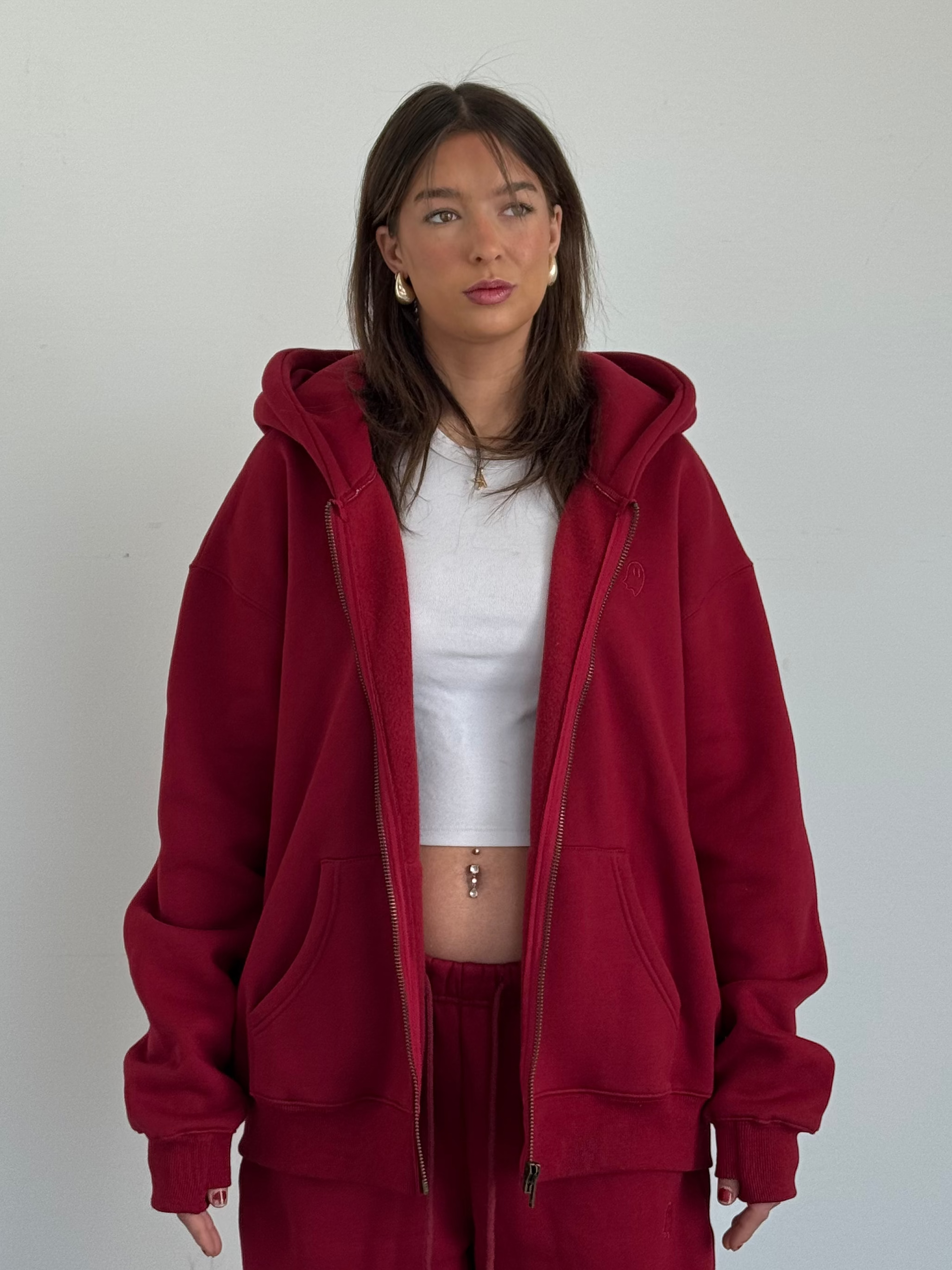 Person wearing a red hoodie and matching pants against a plain background