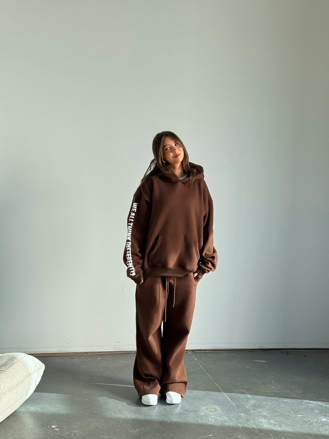 Person wearing a brown tracksuit standing against a plain wall.