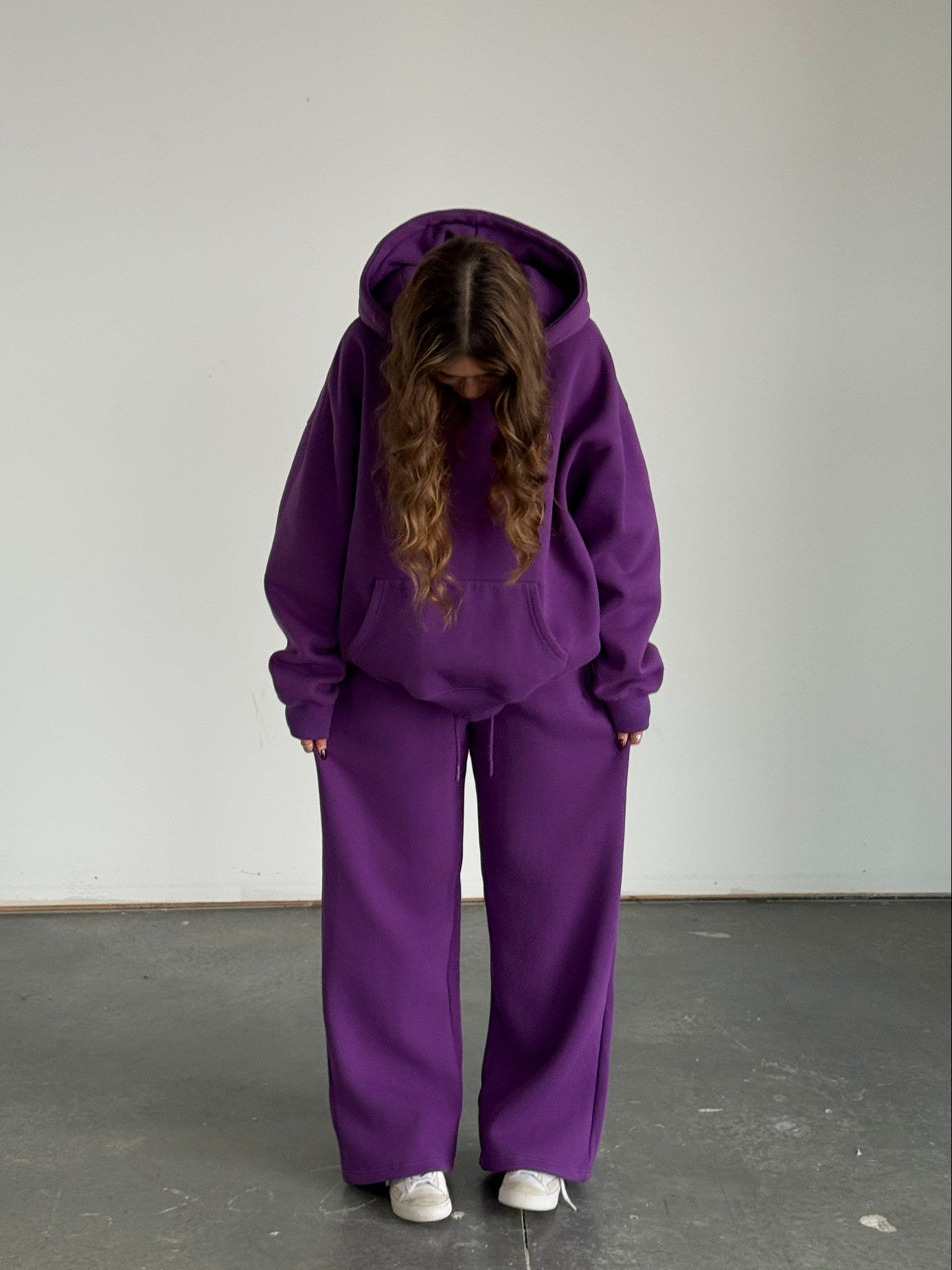 Person wearing a purple hoodie and pants in a minimalistic setting