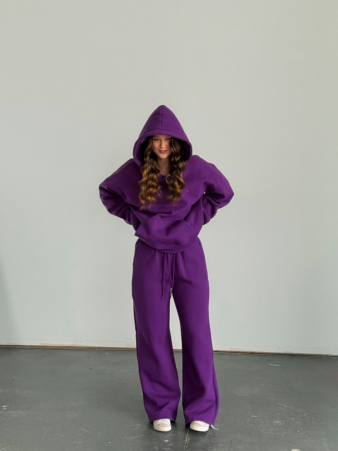 Person wearing a purple hoodie and pants set against a plain background